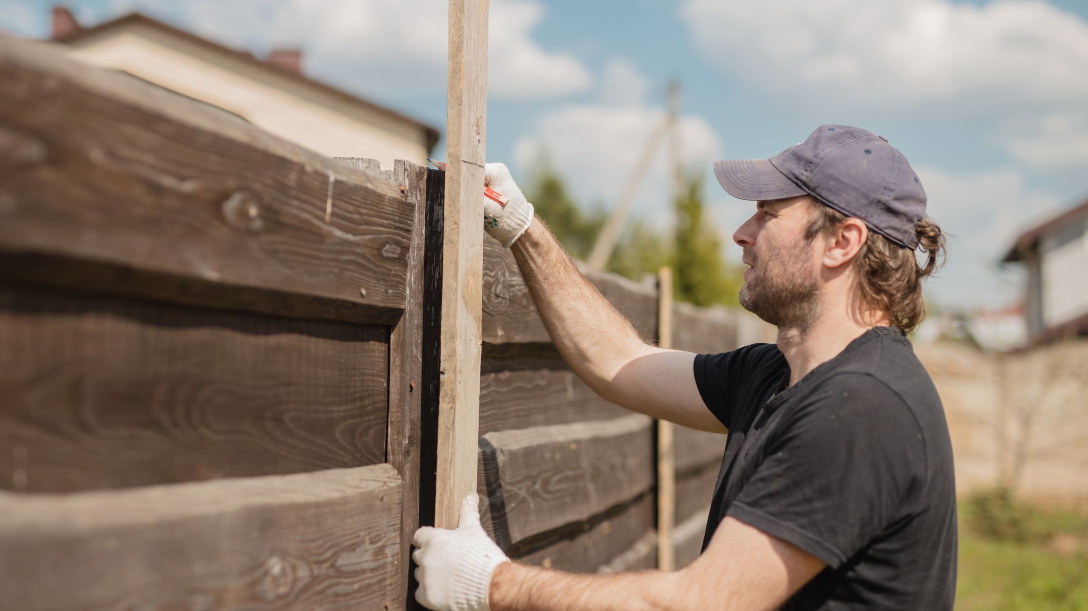 A man repairing a portion of his fence.