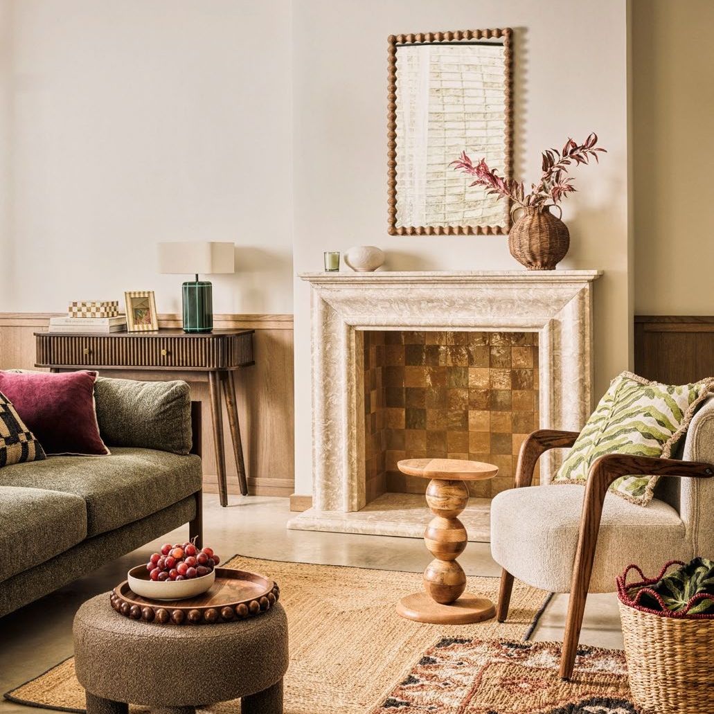 Boho style living room with cream walls, wooden panelling, wooden side tables, green sofa, white armchair and a sisal rug.