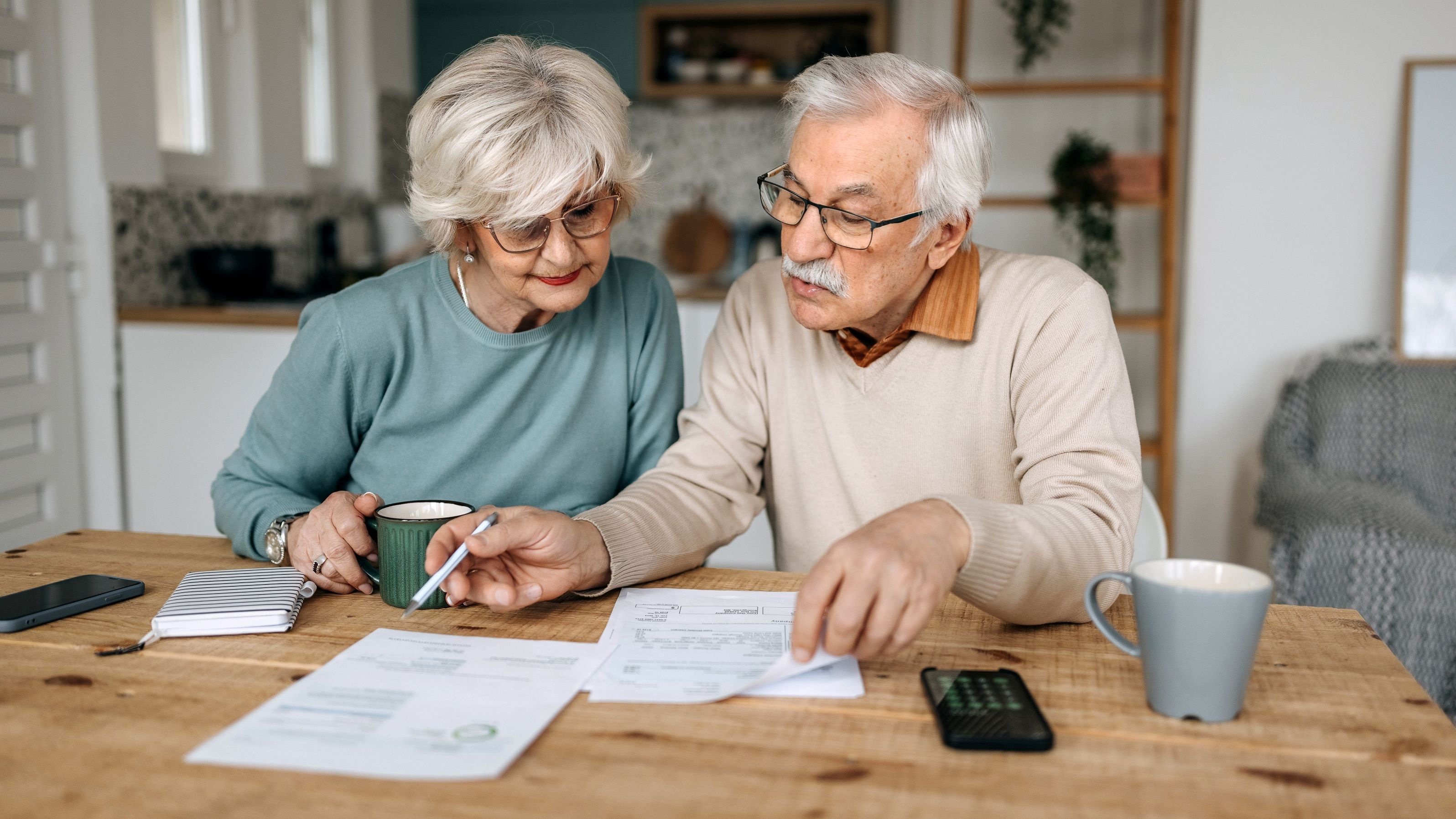 A senior couple goes over their finances together at the kitchen table.