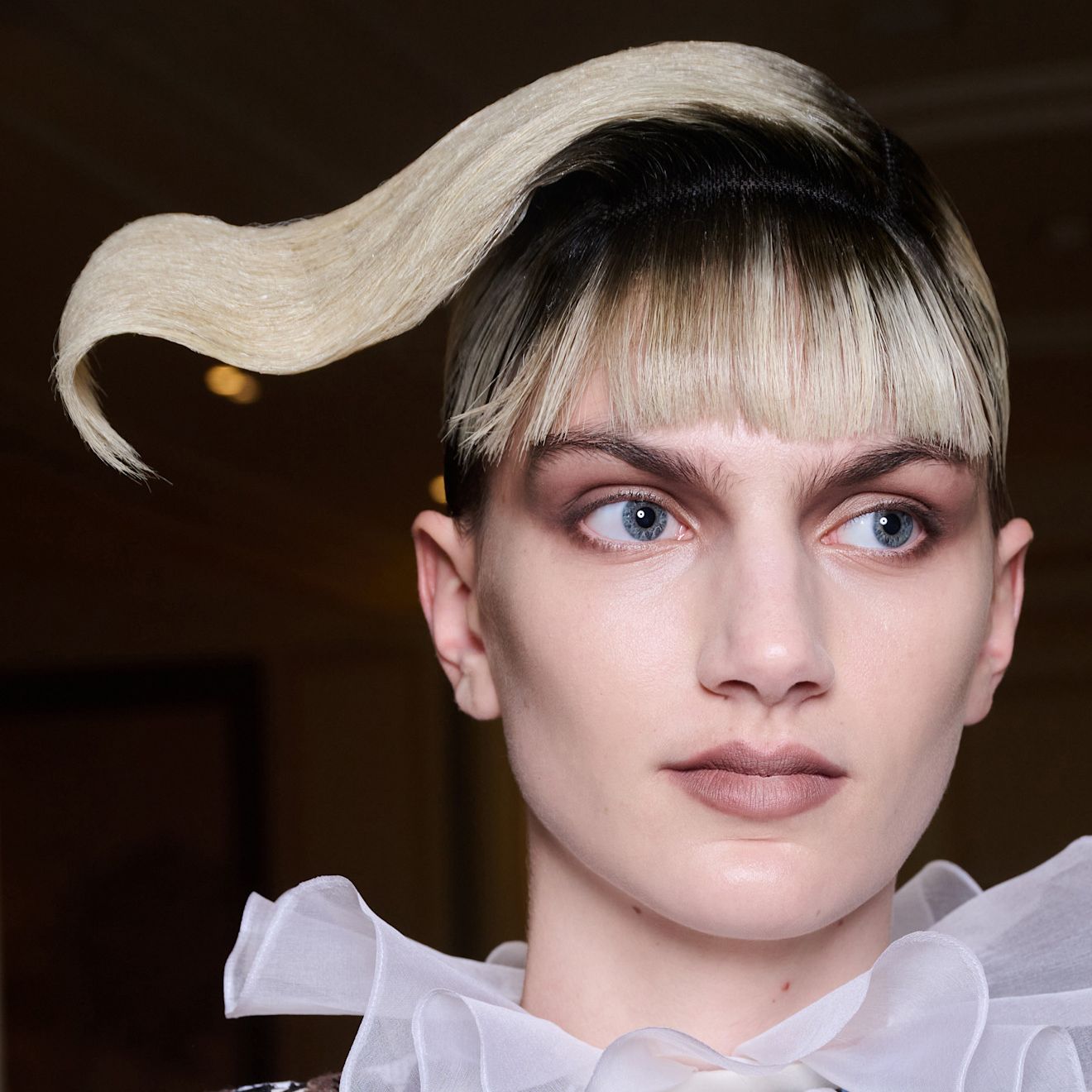 a geometric two tone bang hair style with smokey eye makeup on a person