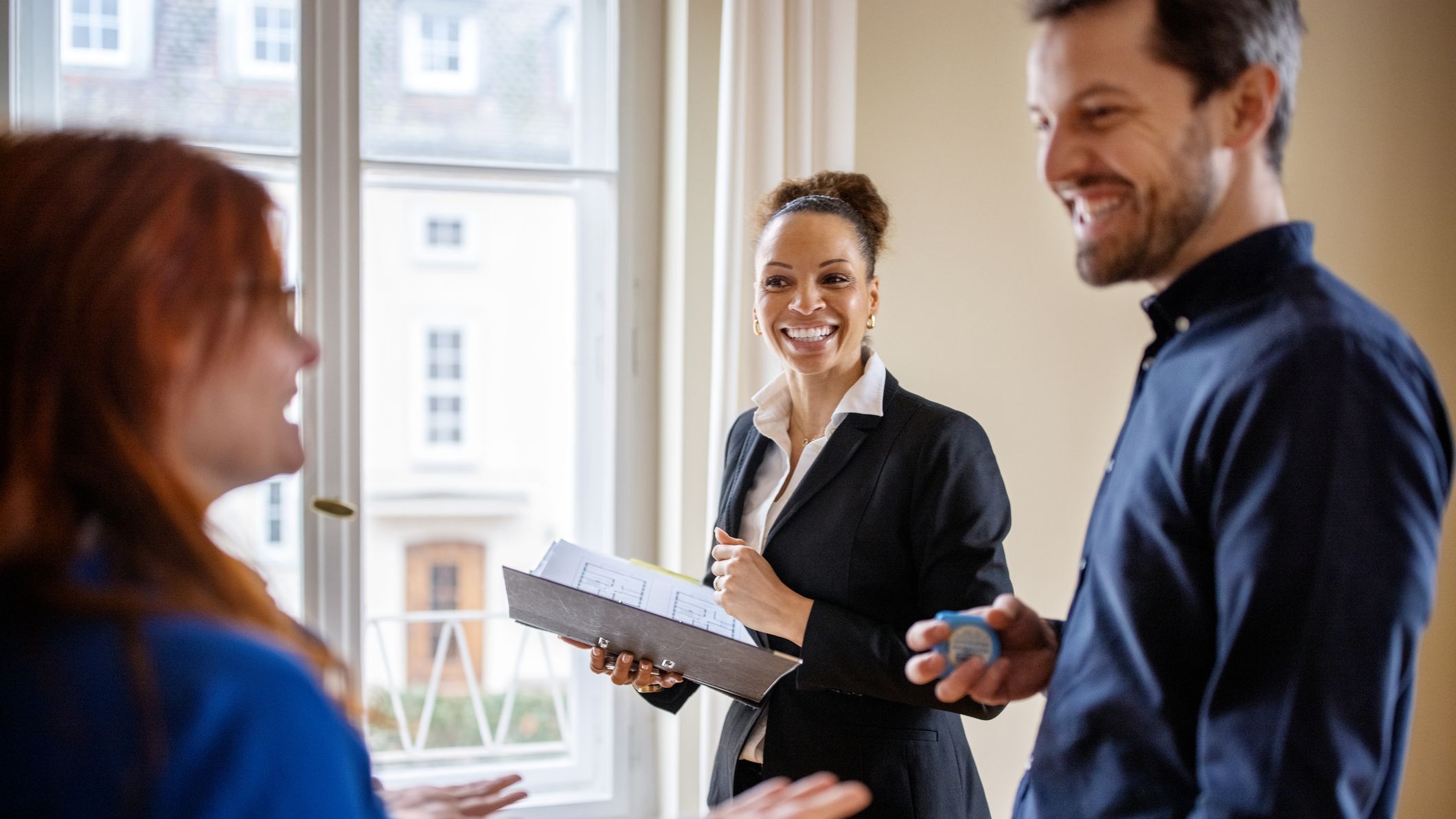 Happy couple looking at a house with a real estate agent