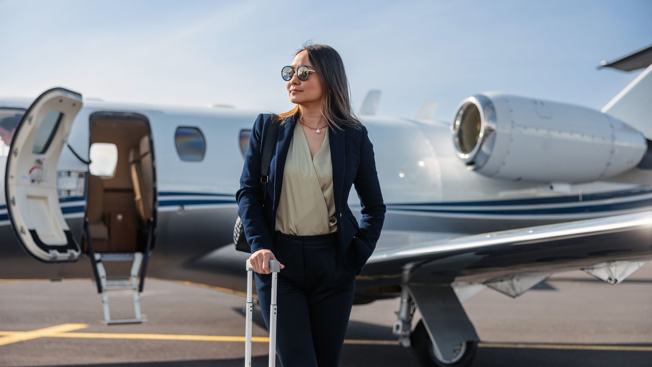 Confident businesswoman standing by a private jet, ready for luxurious travel.