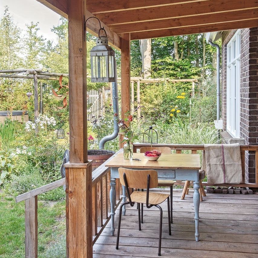 wooden veranda with view over garden and vintage table and chairs