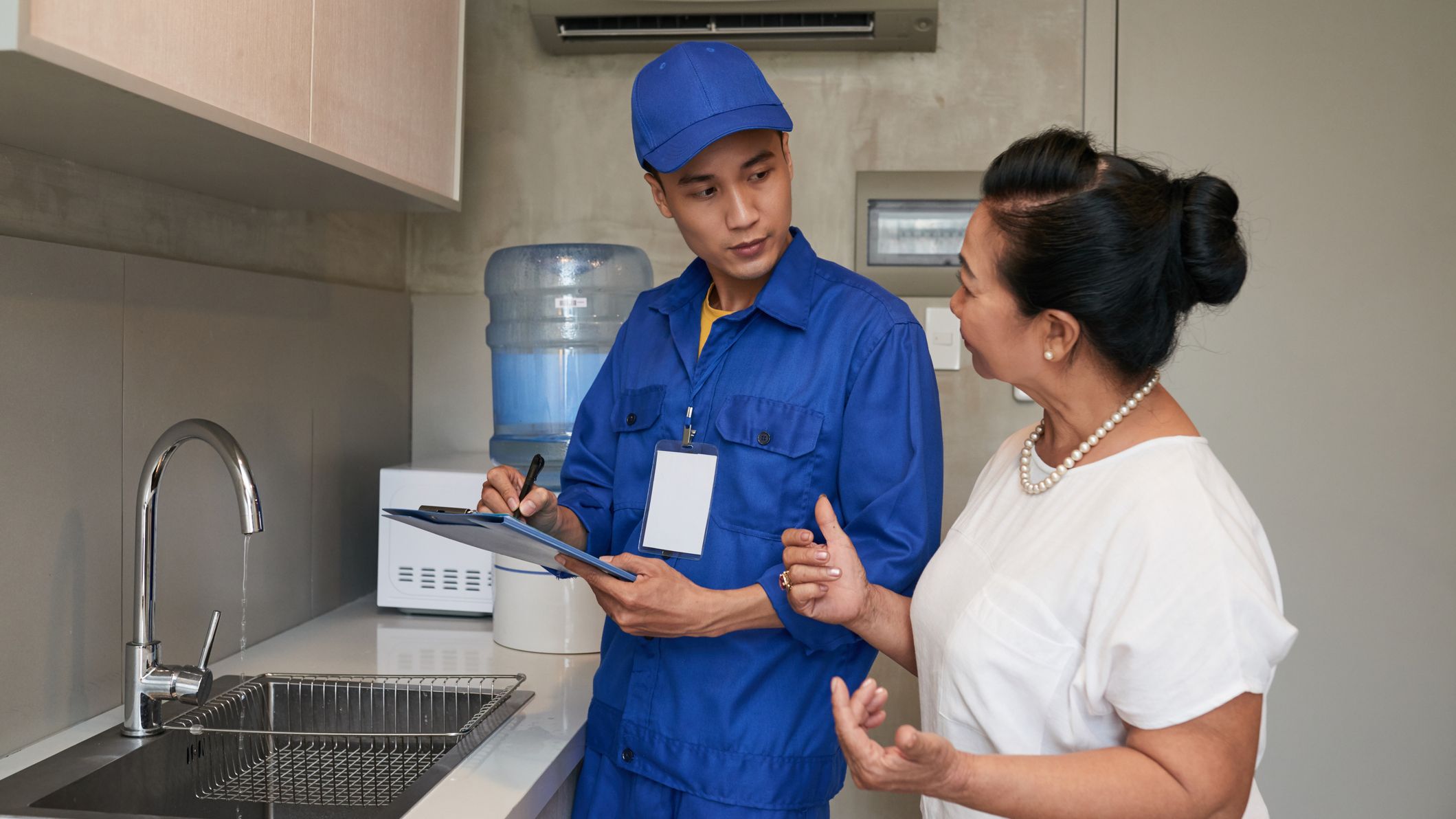 Woman talking to plumber in her kitchen