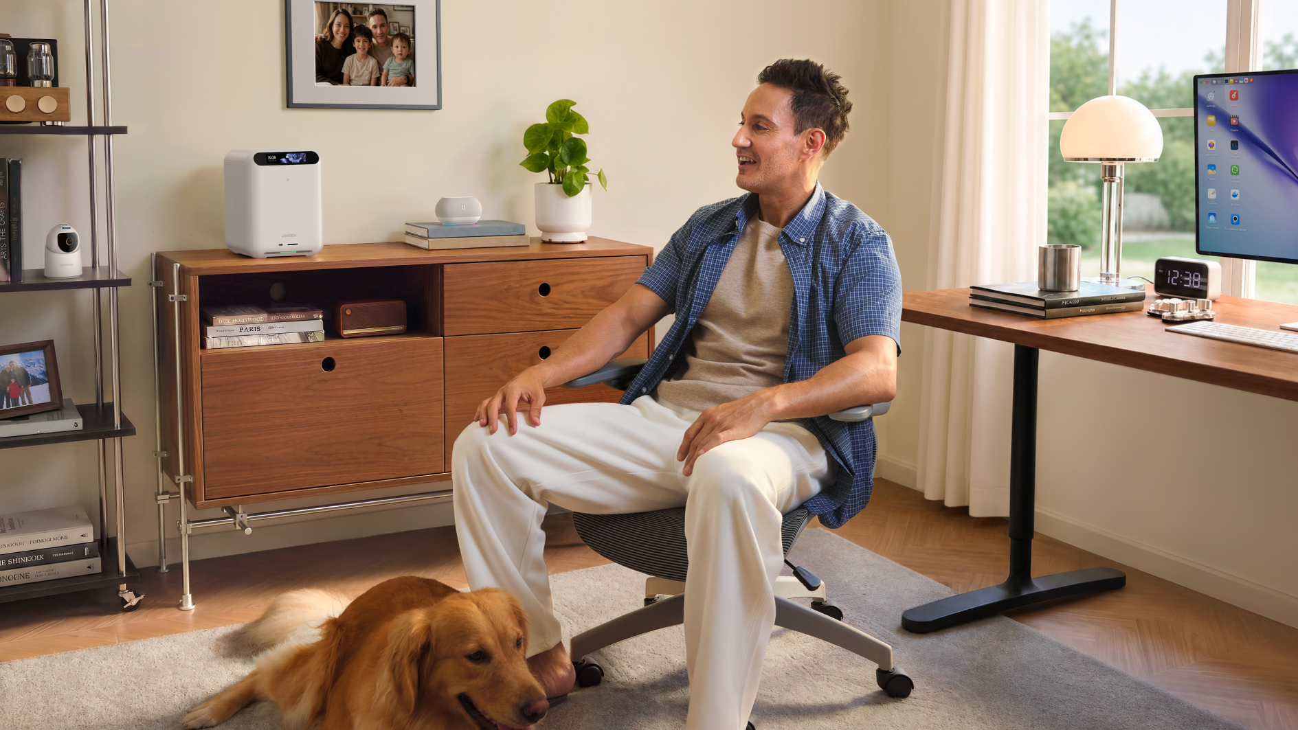 A man sitting at his desk with a dog as his feet.
