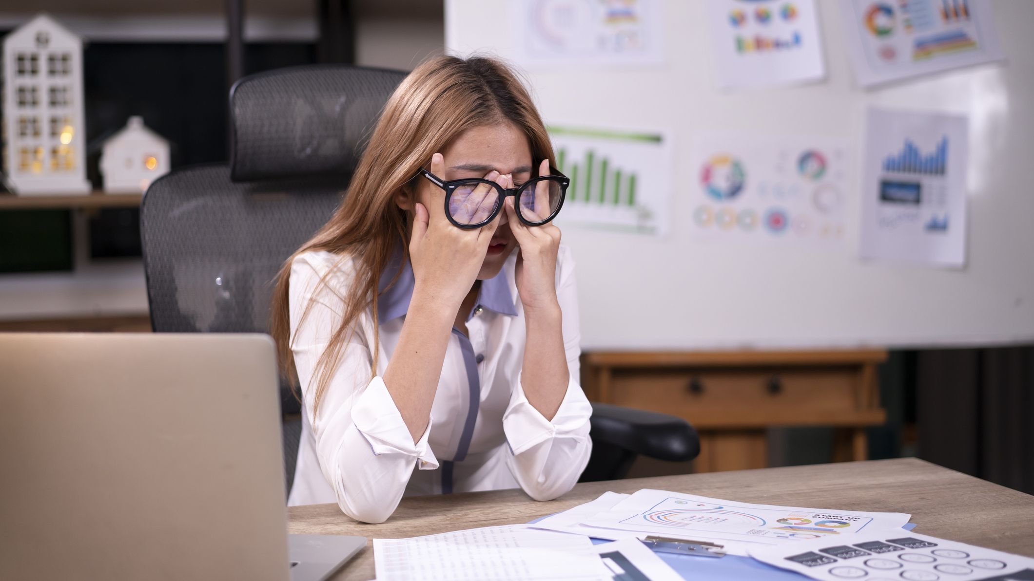 a frustrated woman rubs her nose after going through financial documents
