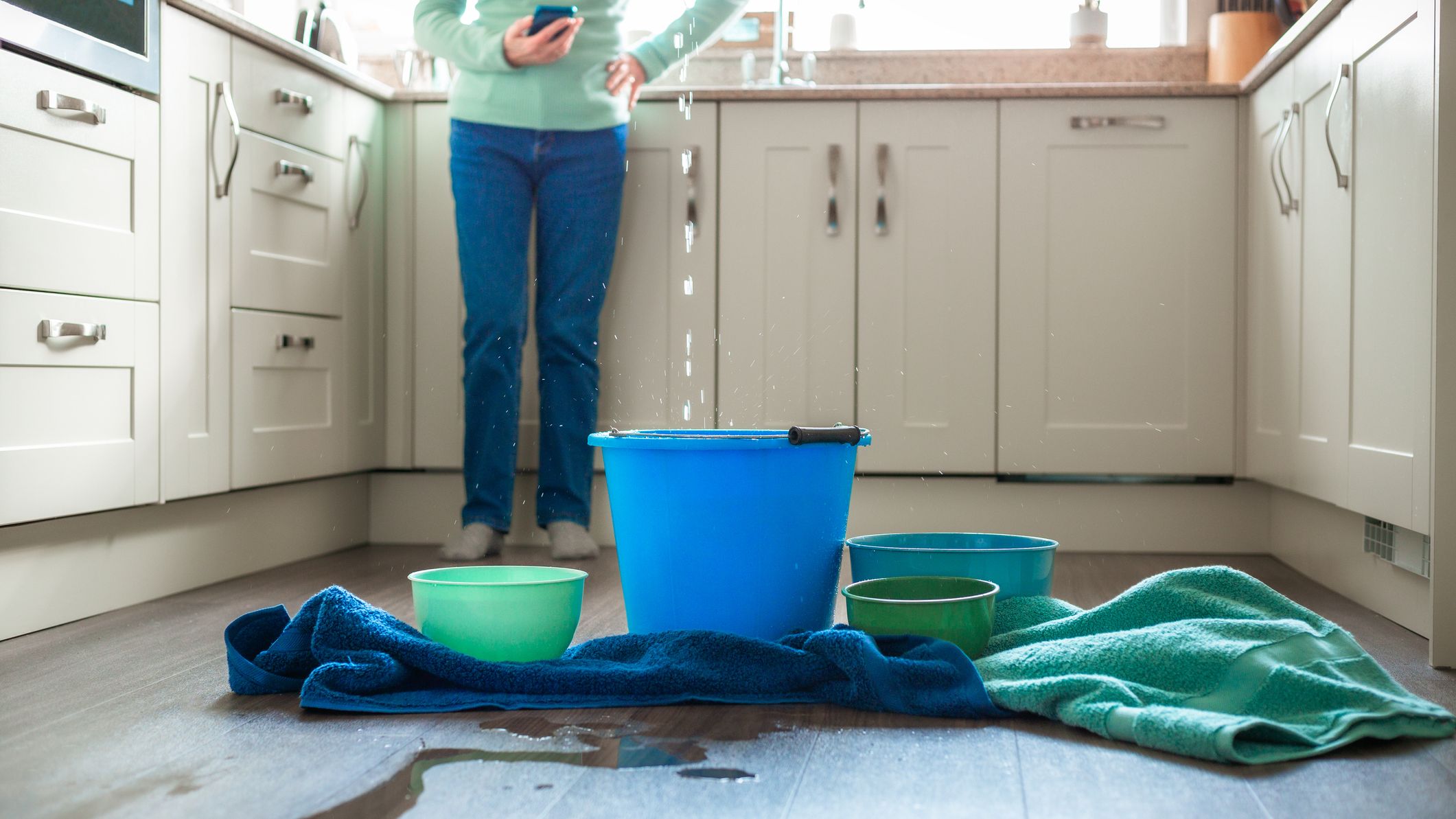 Worried home owner dealing with water leak in the kitchen