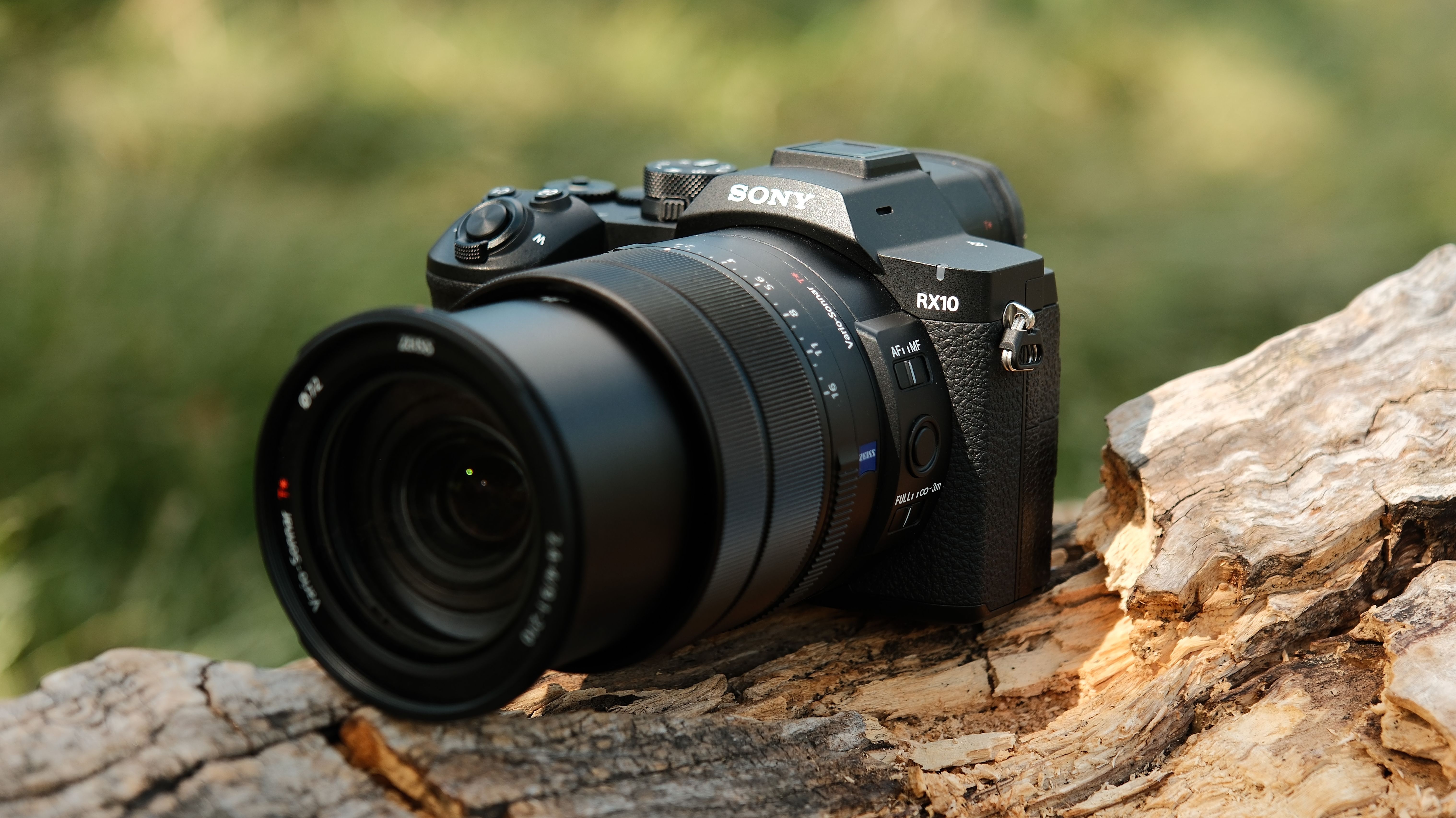 Front three-quarter view of the Sony RX10 V with its lens extended on a fallen tree trunk.