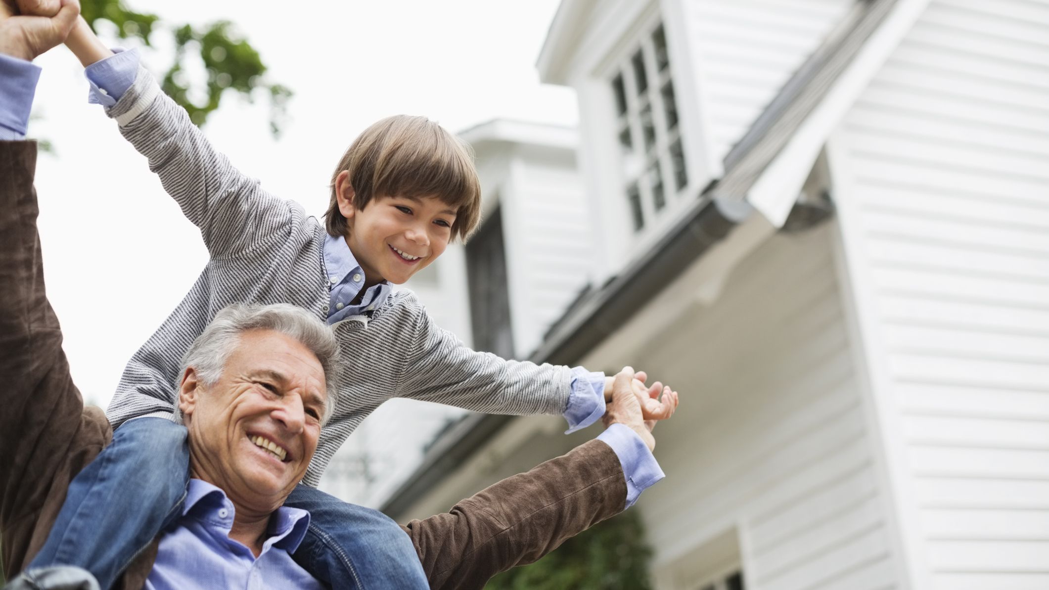 A grandfather carries his grandson on his shoulders.