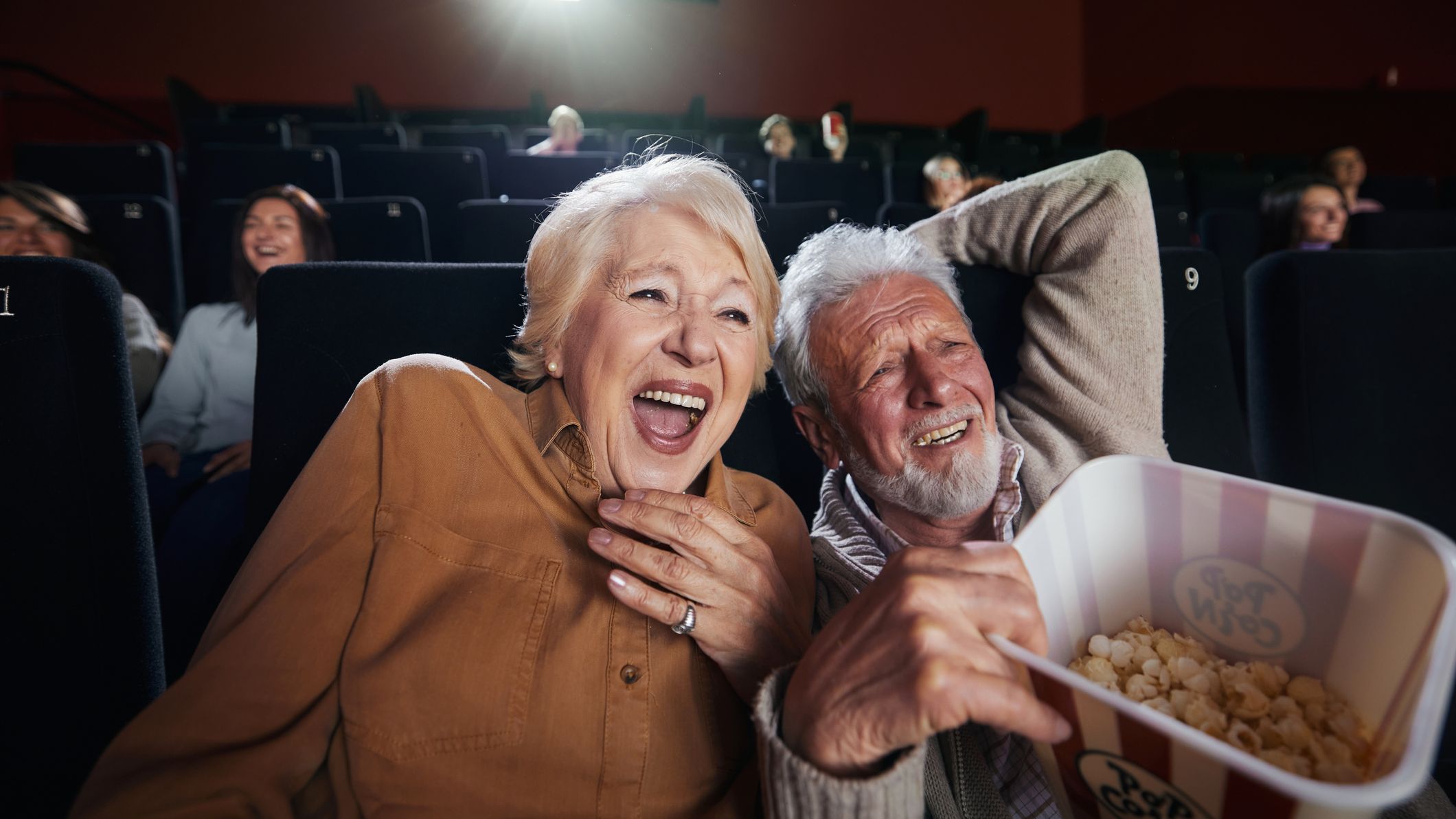 Cheerful senior couple watching funny movie at the theatre.
