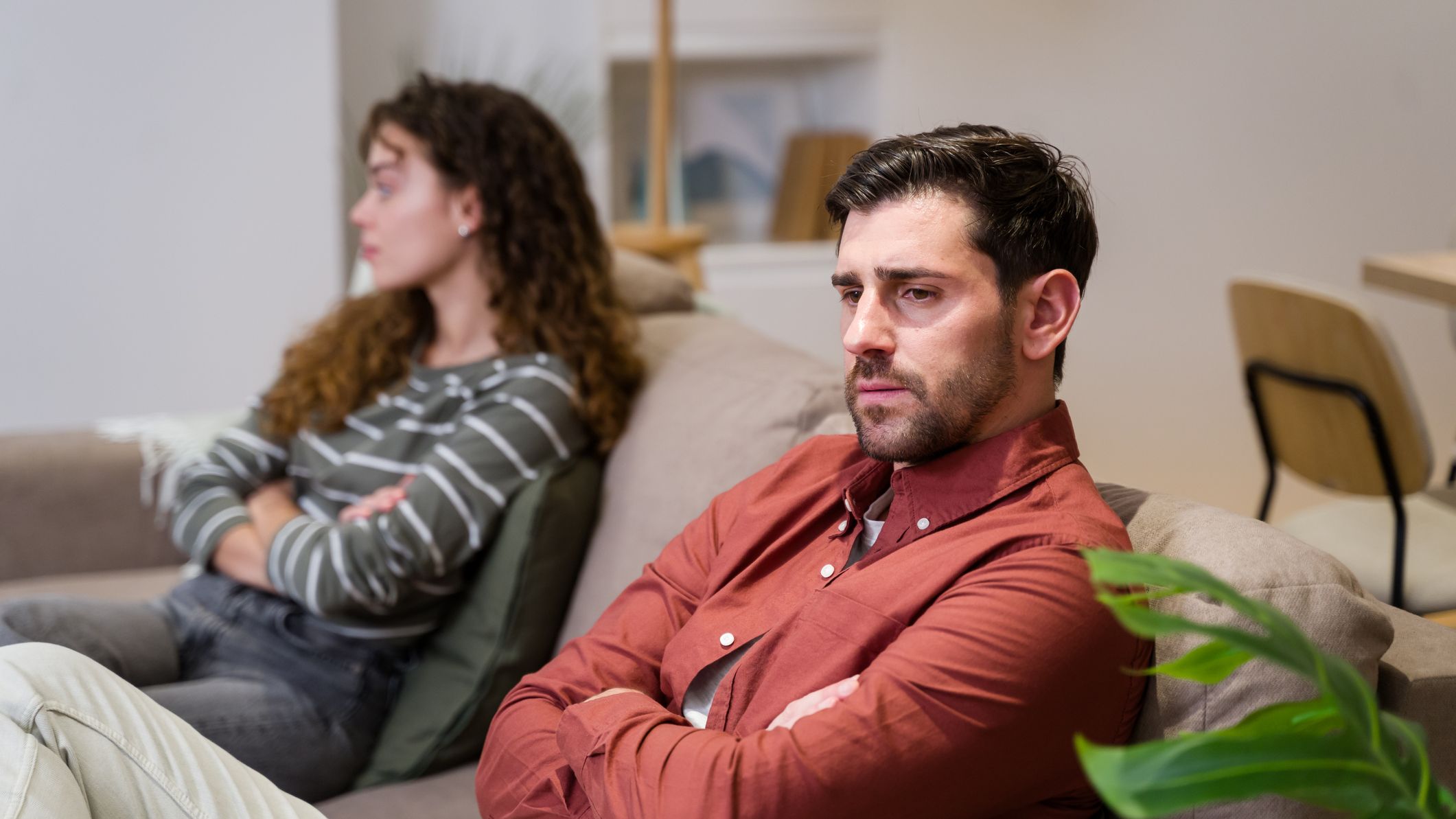 Young couple sitting on sofa at home having relationship problems