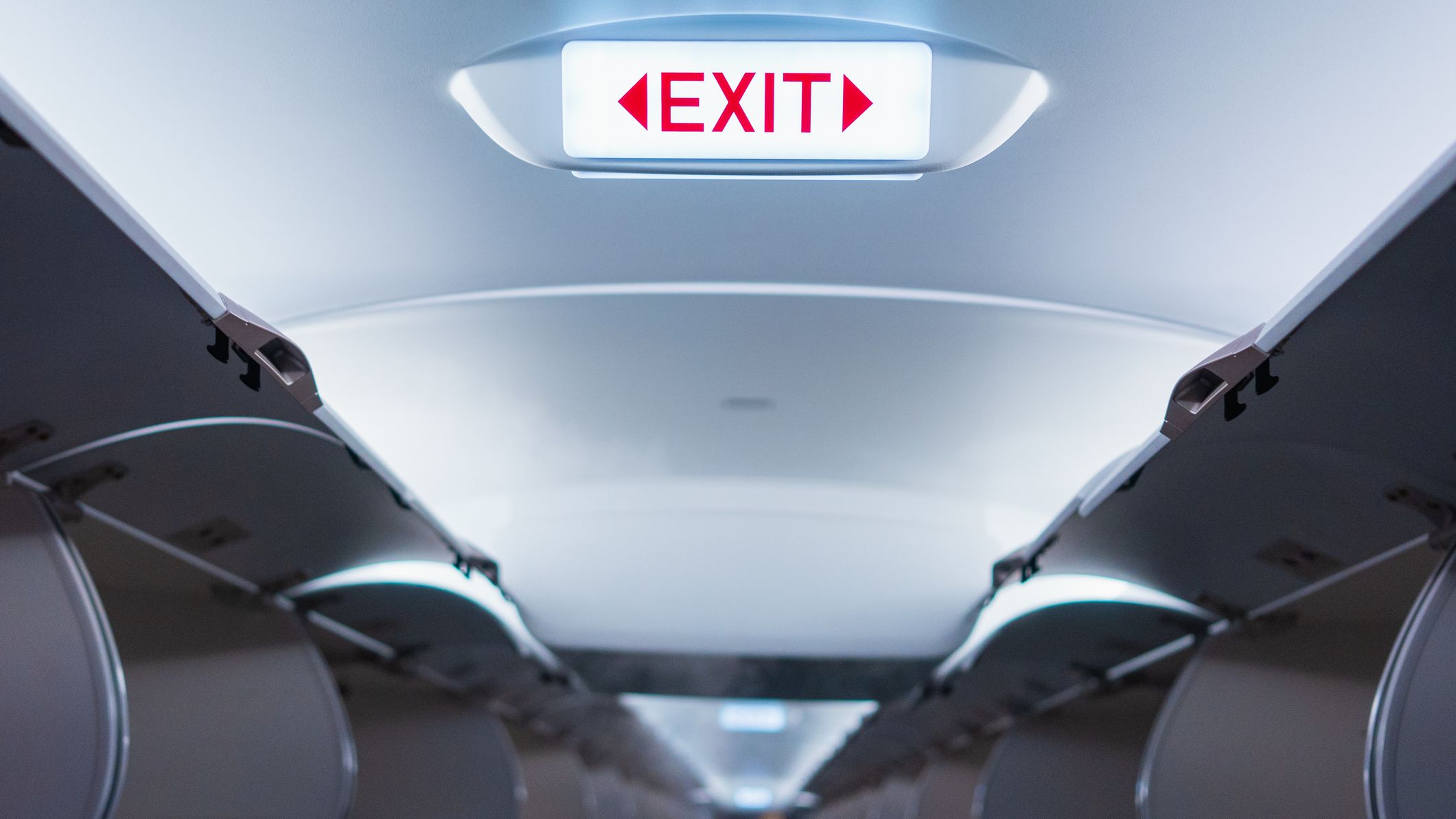 Emergency exit sign on ceiling inside passenger aircraft cabin