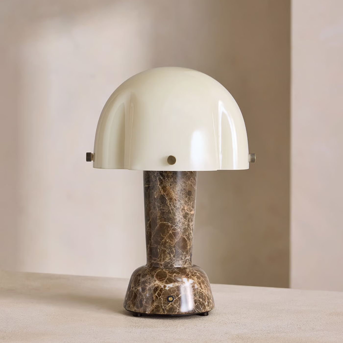 Portable table lamp with a cream dome shade and dark Emperador marble base, featuring brass detailing and a compact, space-saving silhouette.