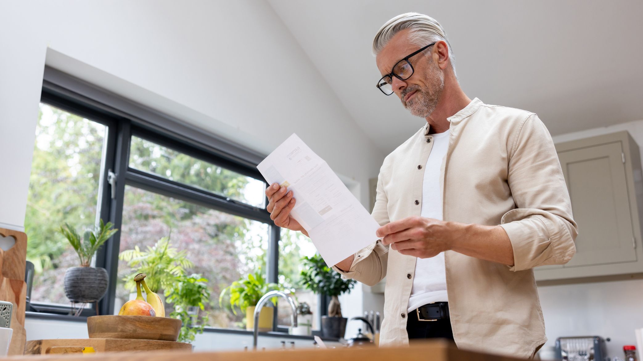 Man at home reading a piece of mail.