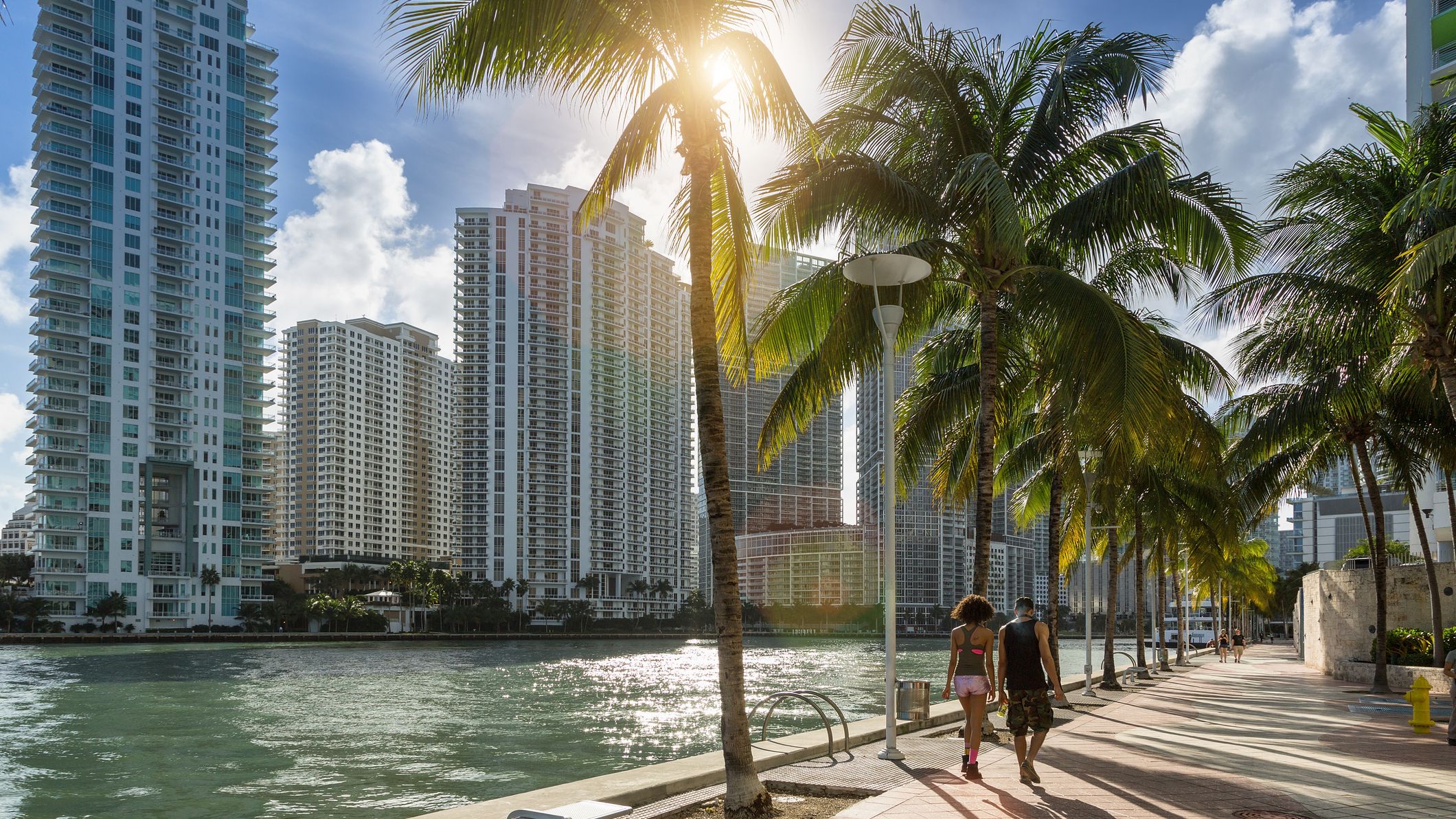 A couple walking along the waterfront beside the Miami skyline.
