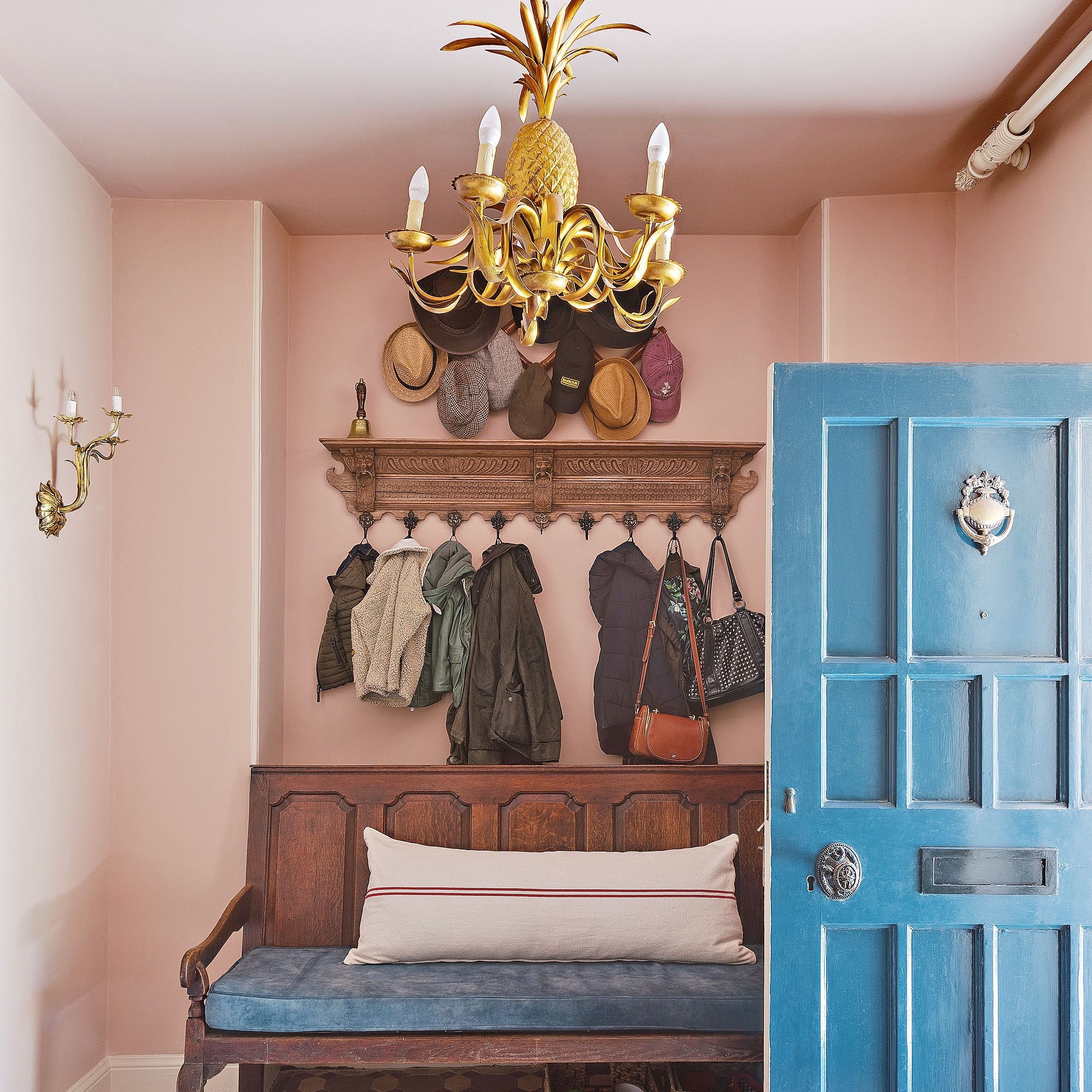 Pink entrance way with vintage wooden bench and coat rack underneath gold pineapple pendant light