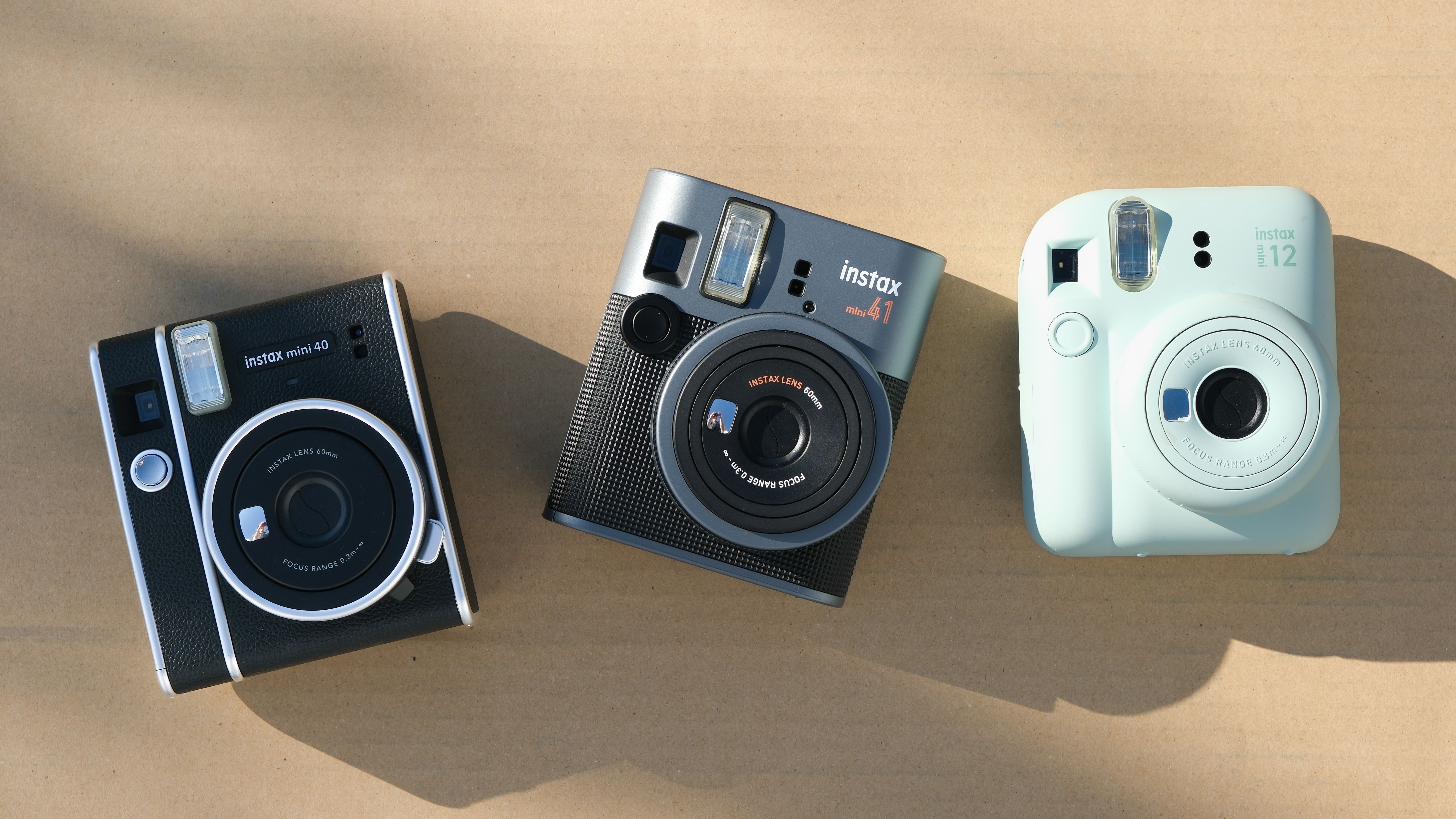 Fujifilm Instax Mini 41 camera next to Fujifilm Instax Mini 40 and Fujifilm Instax Mini 12 cameras