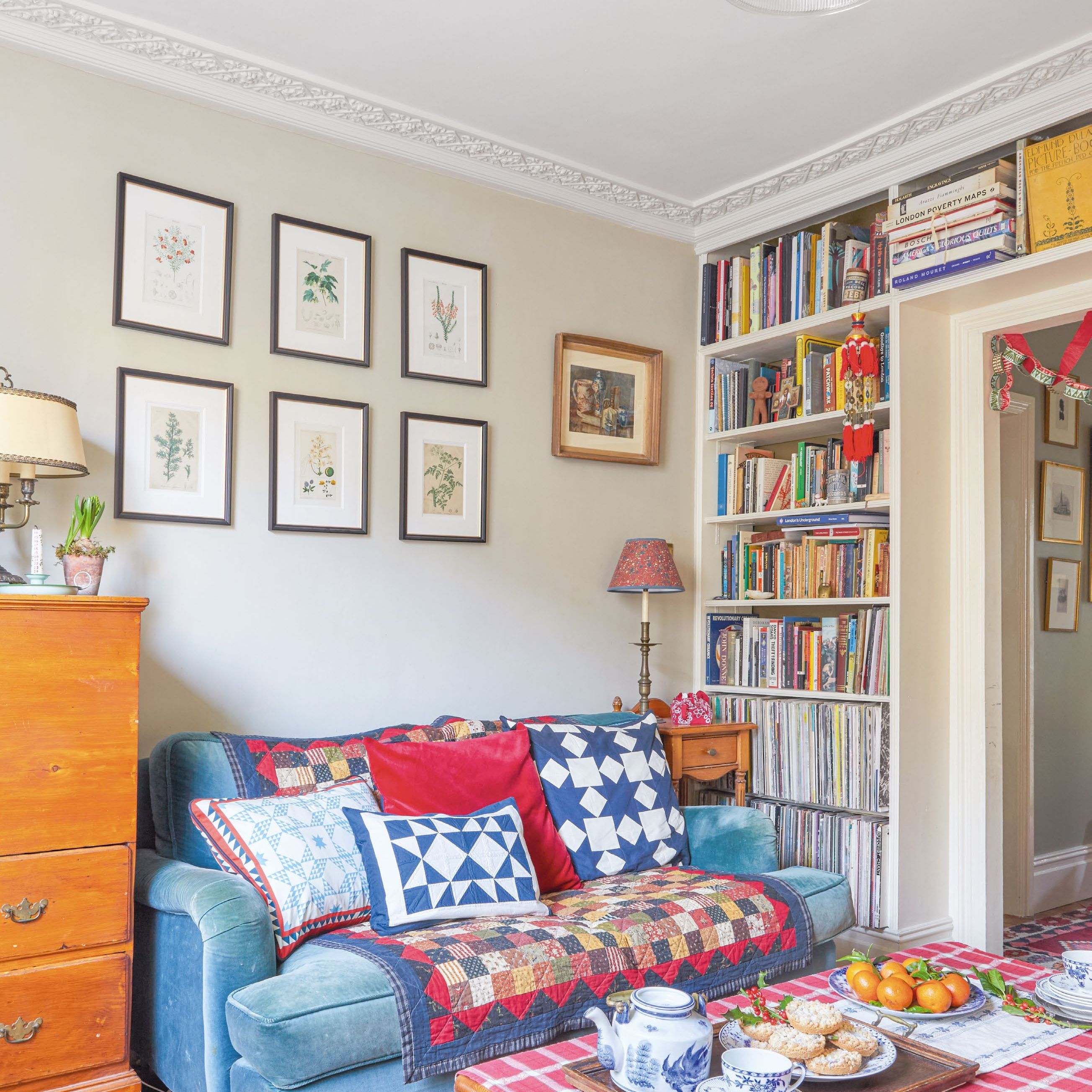 side shot of living room with sofa covered in patchwork cushions and throw and built-in bookcases around doorway