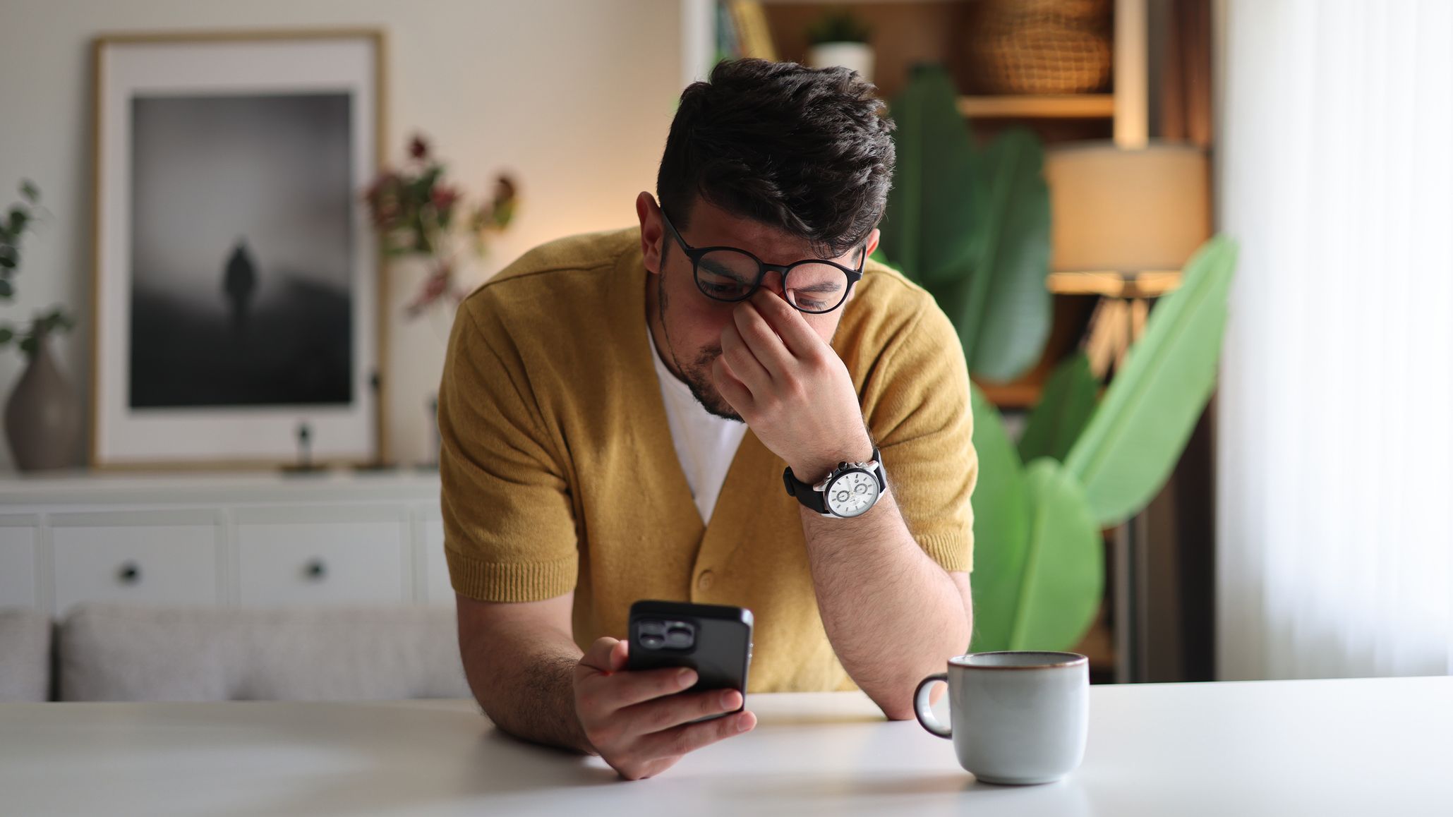 a man rubs the bridge of his nose after reading something frustrating