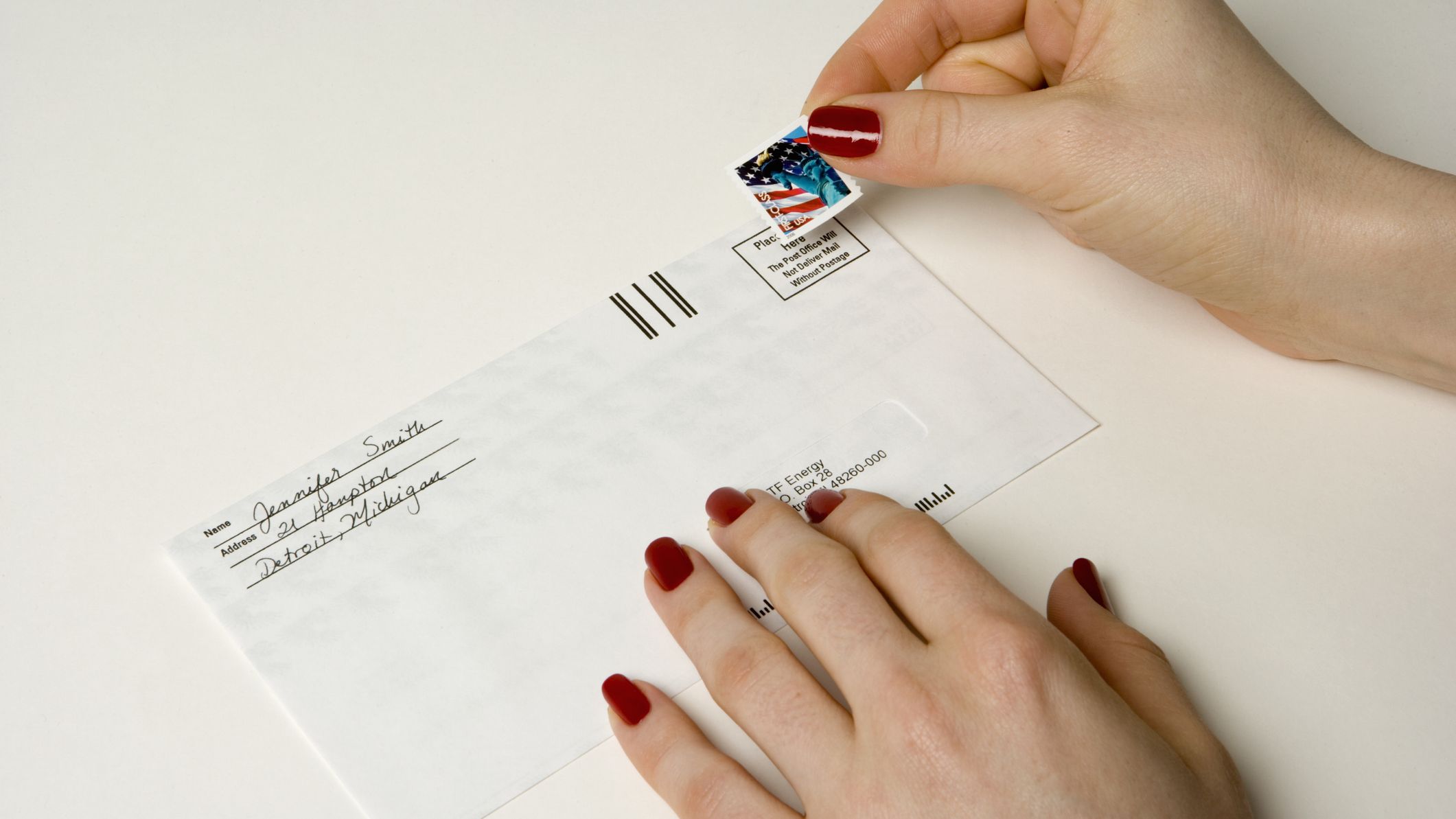 Woman pasting postage stamp on envelope, elevated view