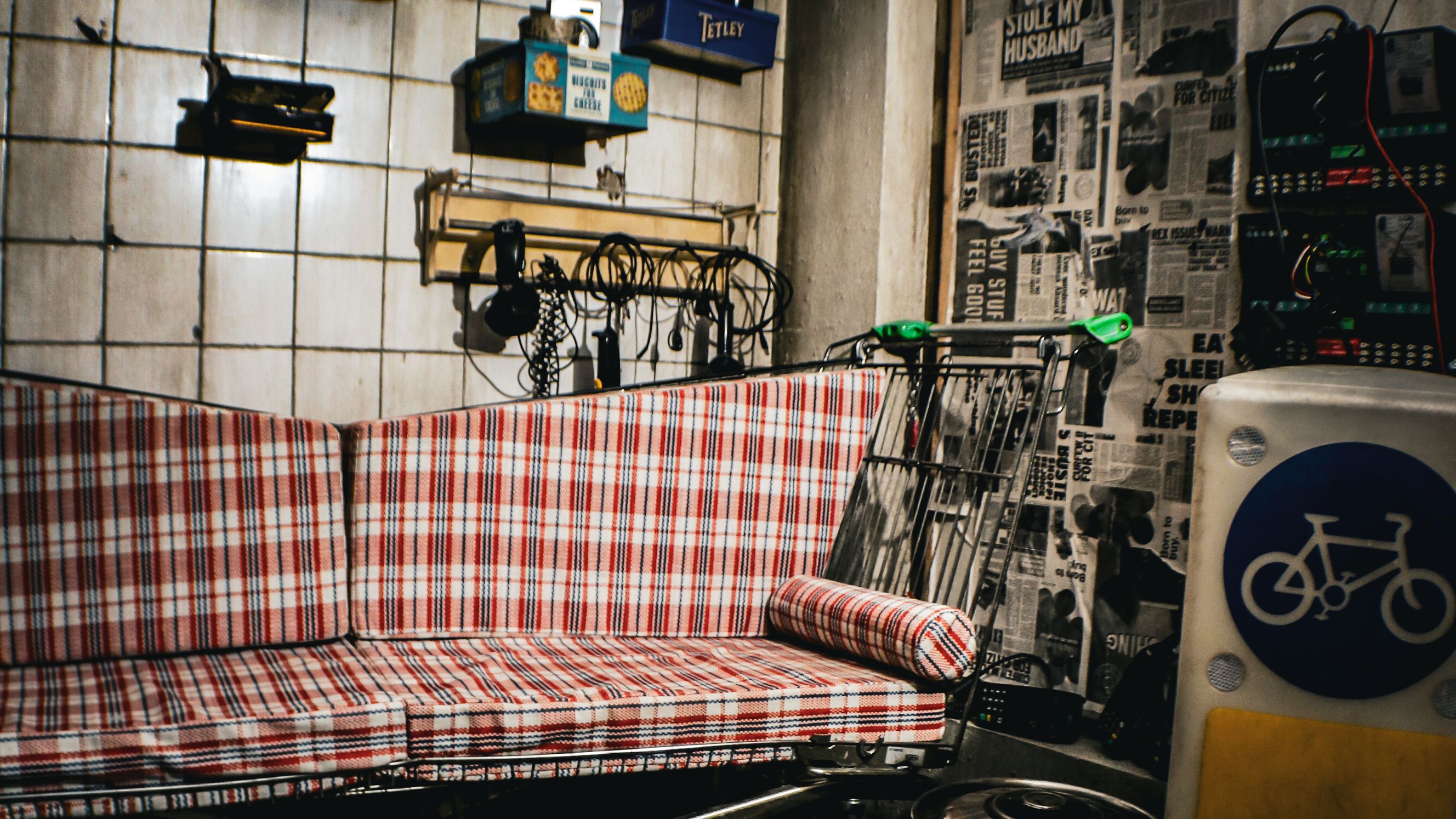 an image of one of the rooms in Absurd City with a wing-shaped soga, a toled and newspapered wall, and different cookware scattered across the centre