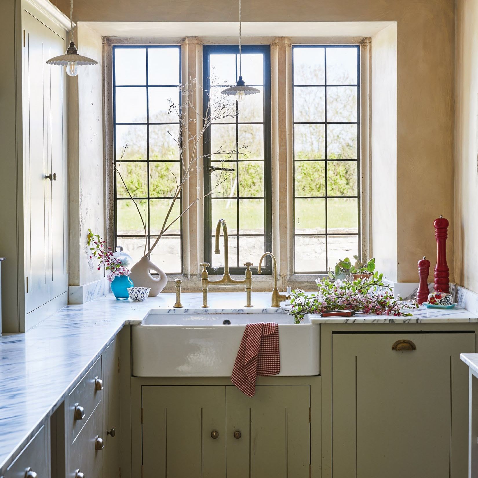 View towards leaded windows above a butlers sink in country kitchen with sage cabinets
