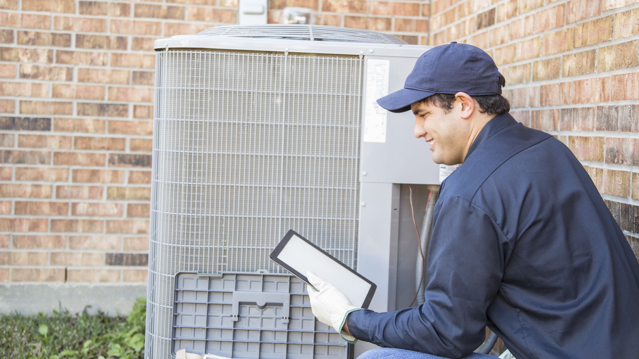 Blue collar air conditioner repairman at work.