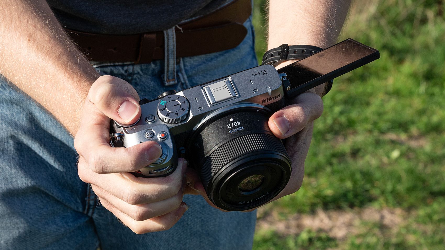 Mike Harris wearing a t-shirt and jeans holding the Nikon Z5IIC on a green background