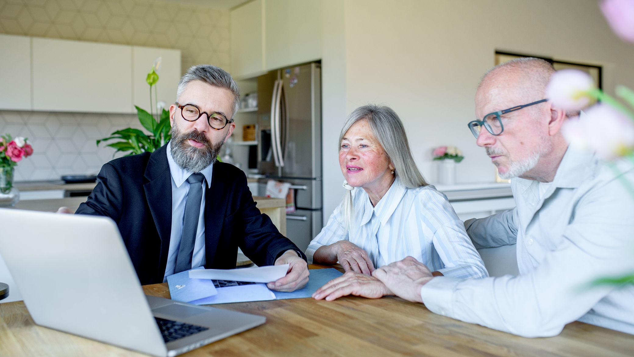 Elderly couple talking with financial advisor about budget and investments.