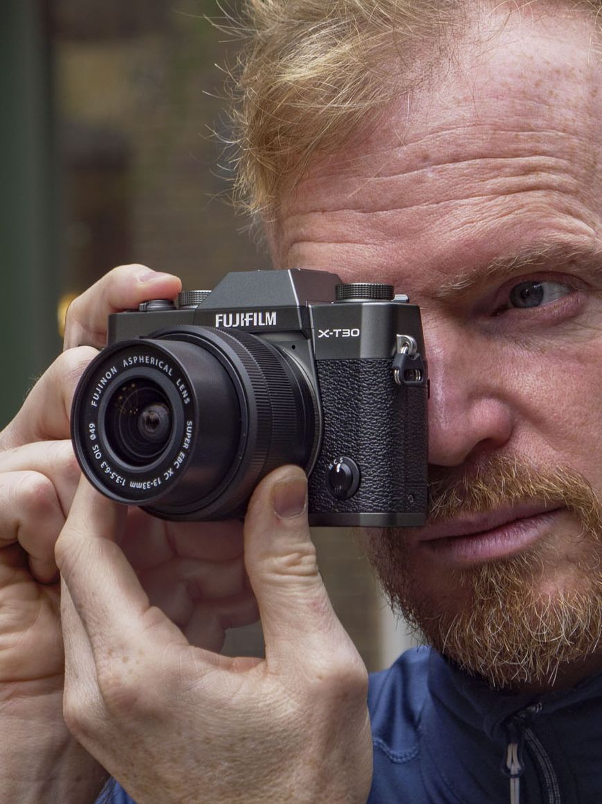 Man holding the Fujifilm X-T30 III camera up to his eye, on London street