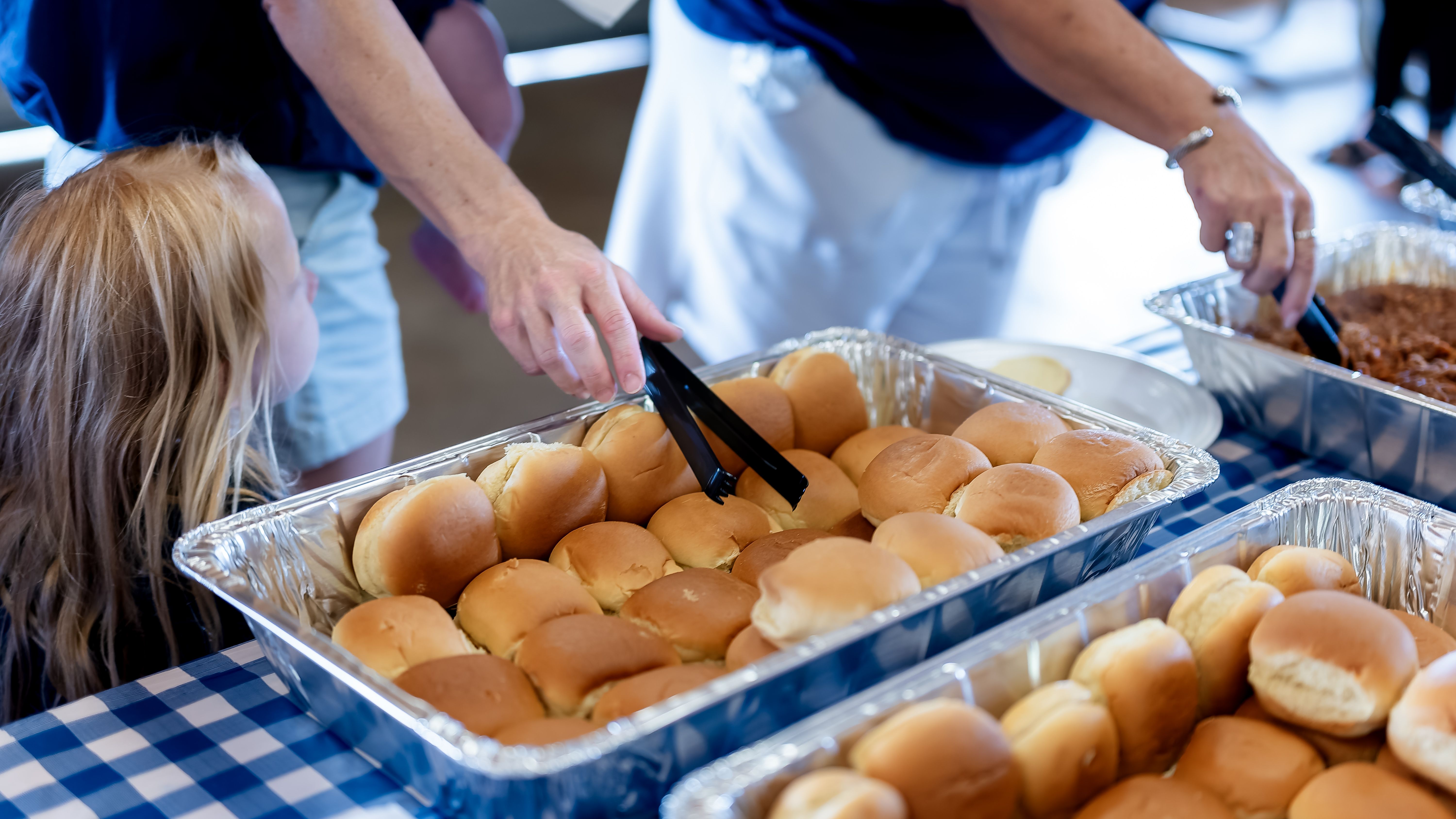 People serving themselves food from a buffet at a family reunion.