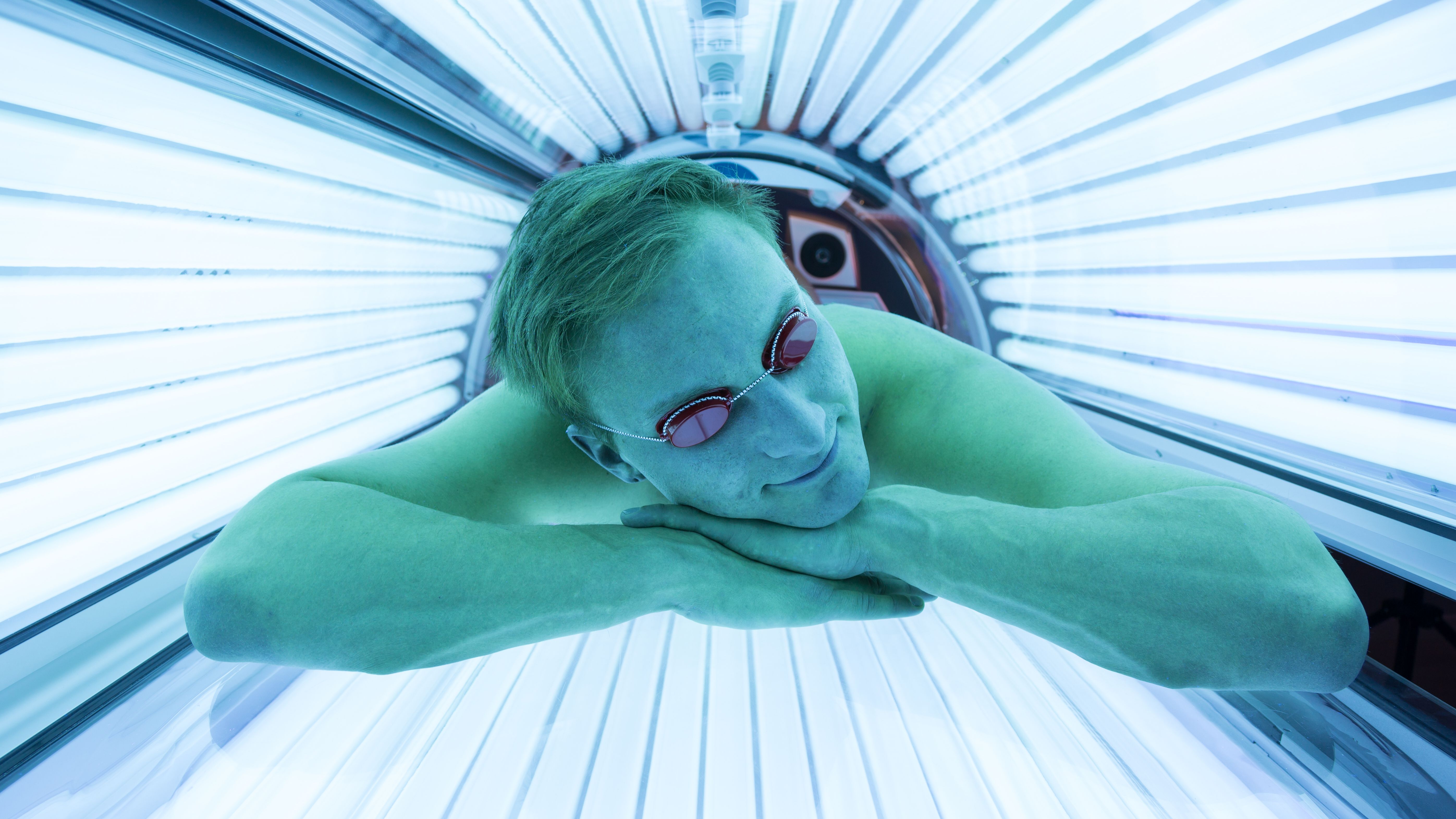 Man with sunglasses on tanning bed in solarium