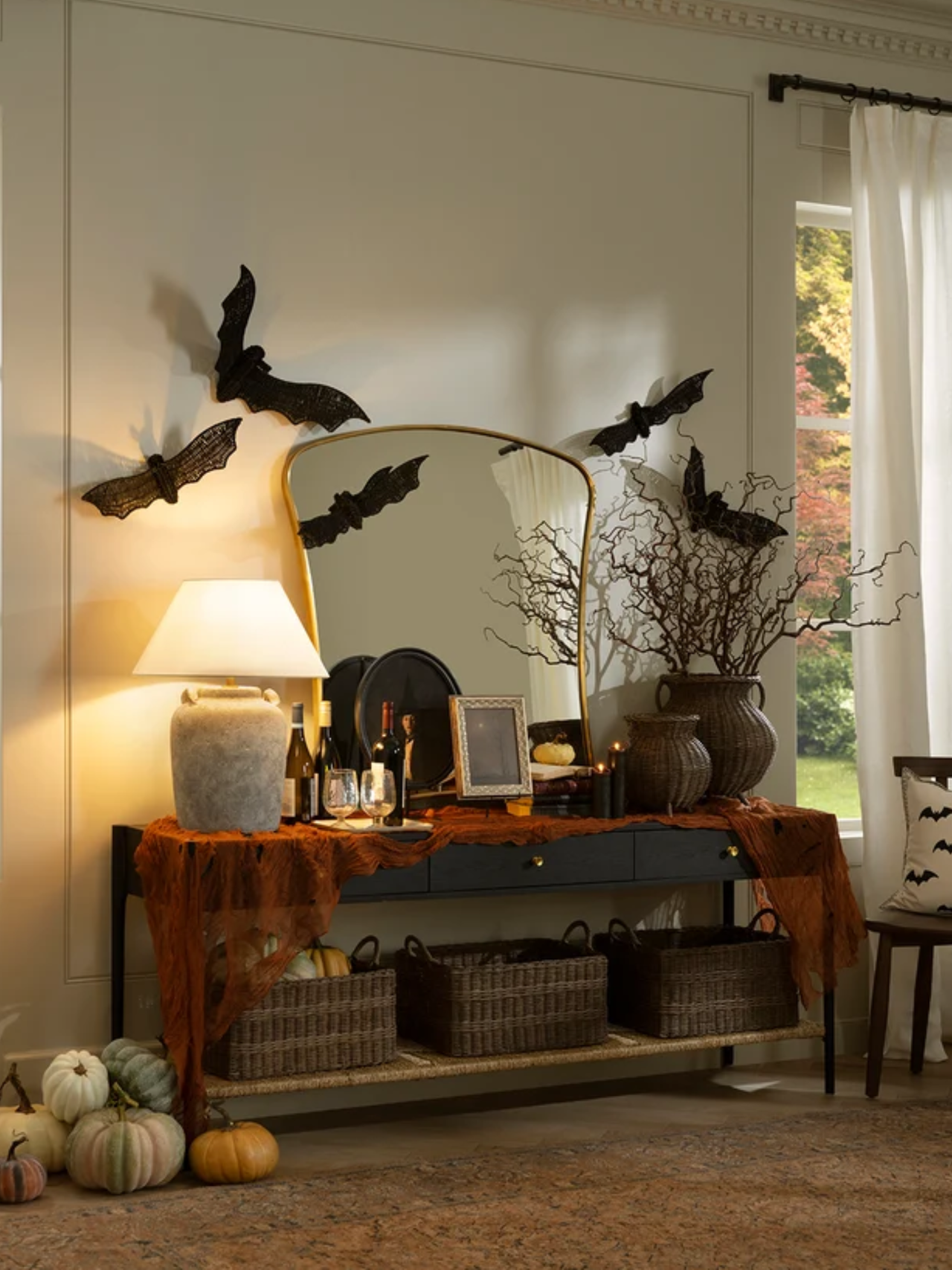 Cozy Halloween console vignette by Shea McGee, featuring wicker vases, aged branches, and wicker bats as wall art.