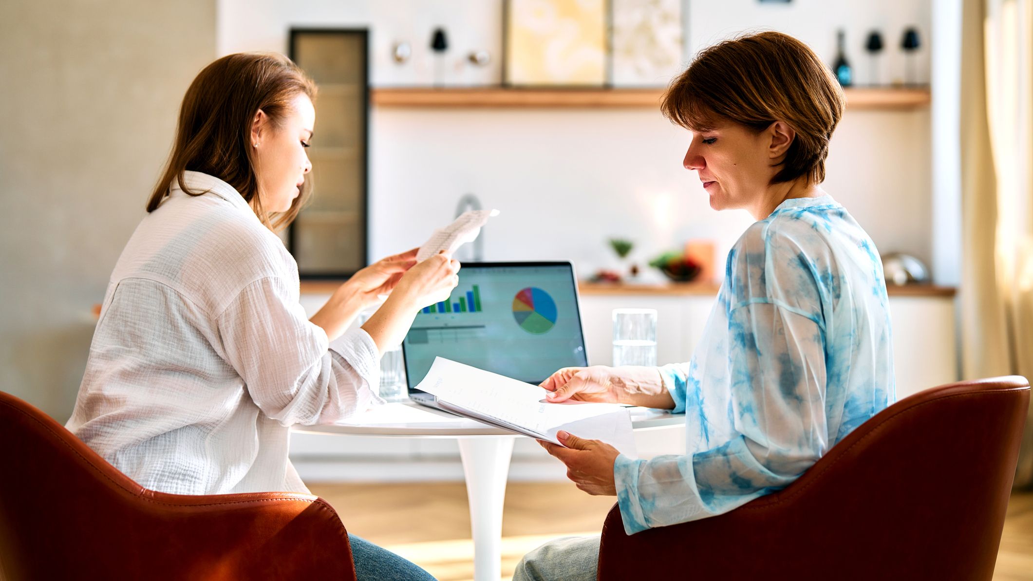 Women planning finances with charts on laptop at home