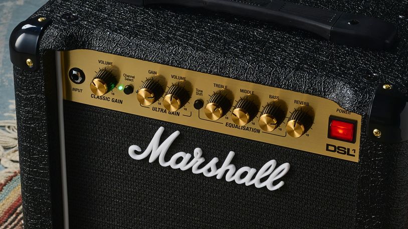 A Marshall DSL1CR tube amp on a rug with footswitch and guitar cable