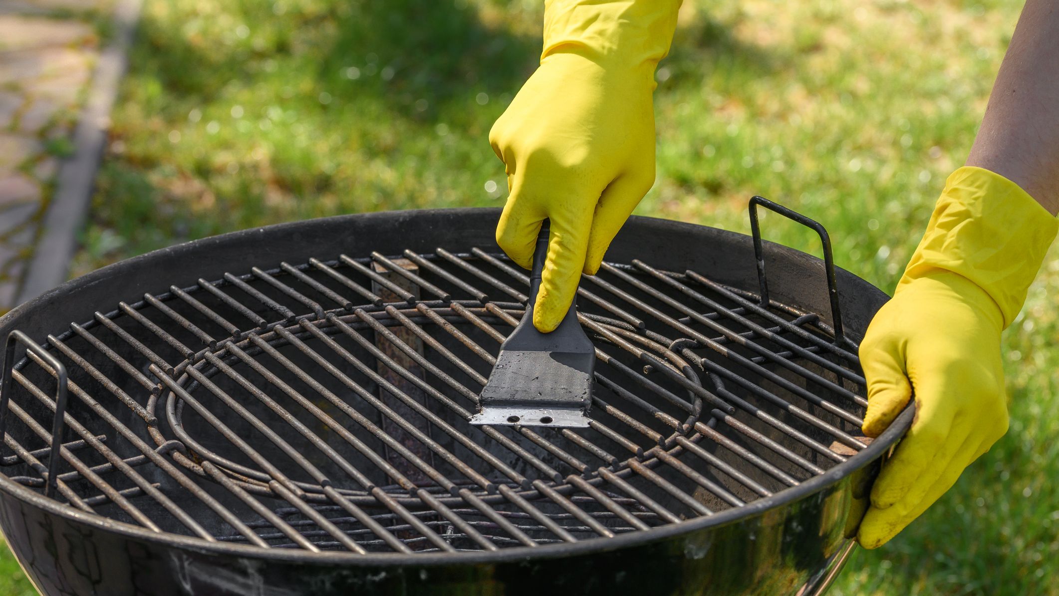 Washing and preparing the metal grate with a blade and yellow protective gloves
