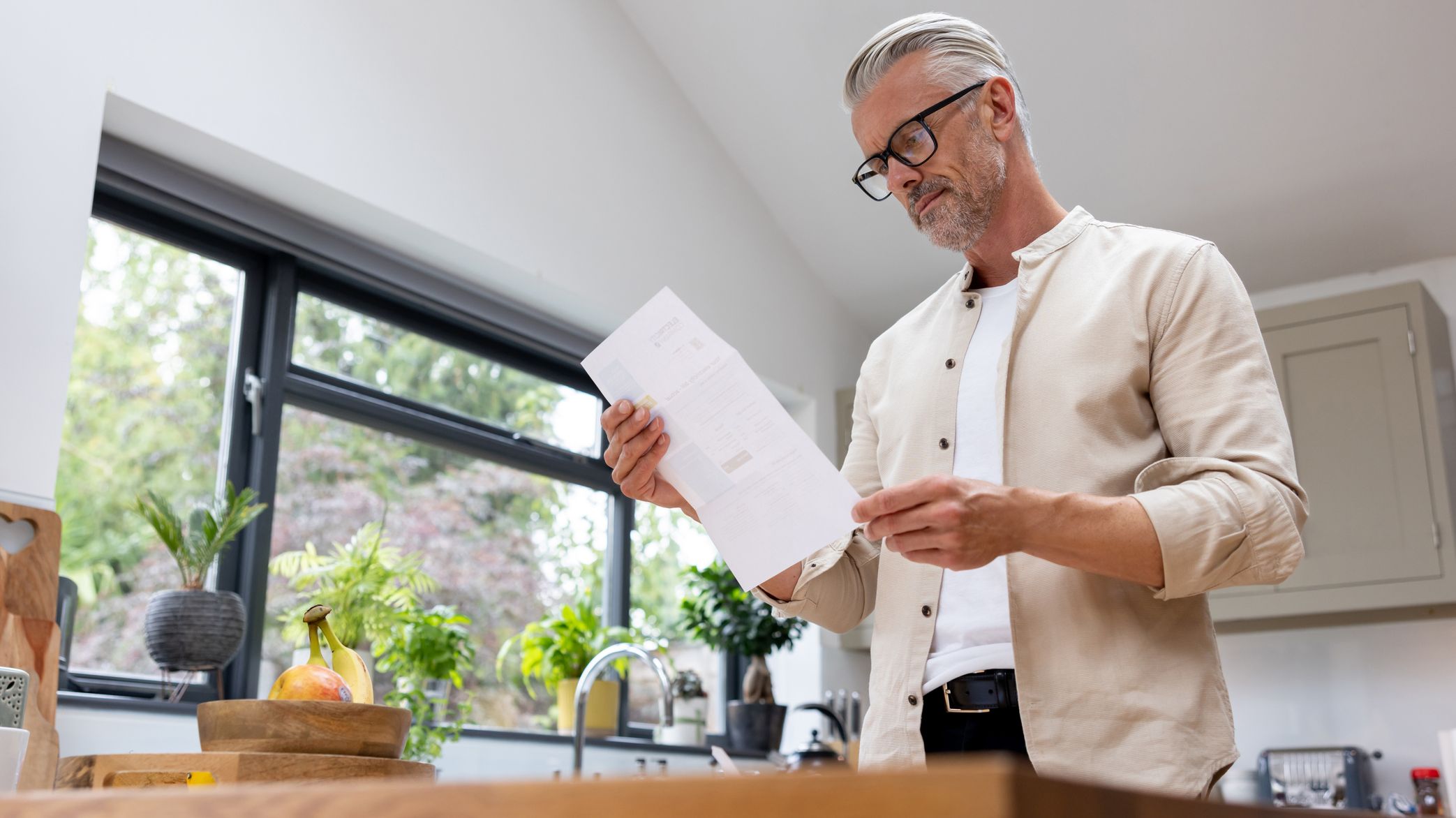 Man at home reading a piece of mail.