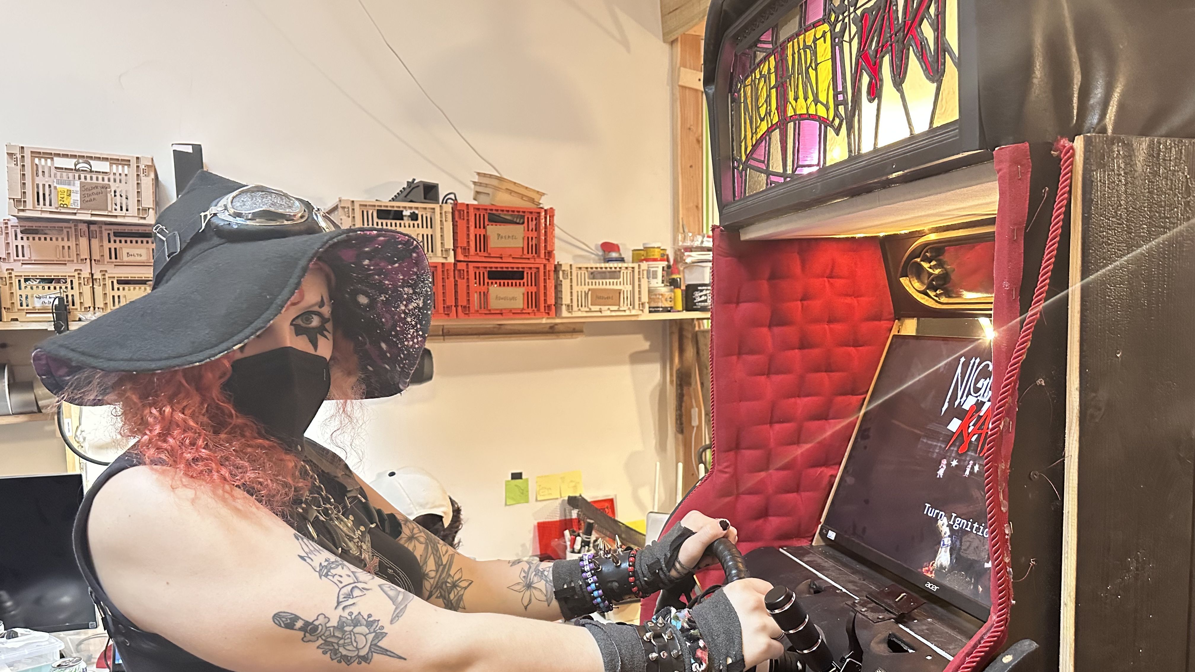Lilith Walther sits in front of the Nightmare Kart arcade cabinet at the Arcade Commons workshop