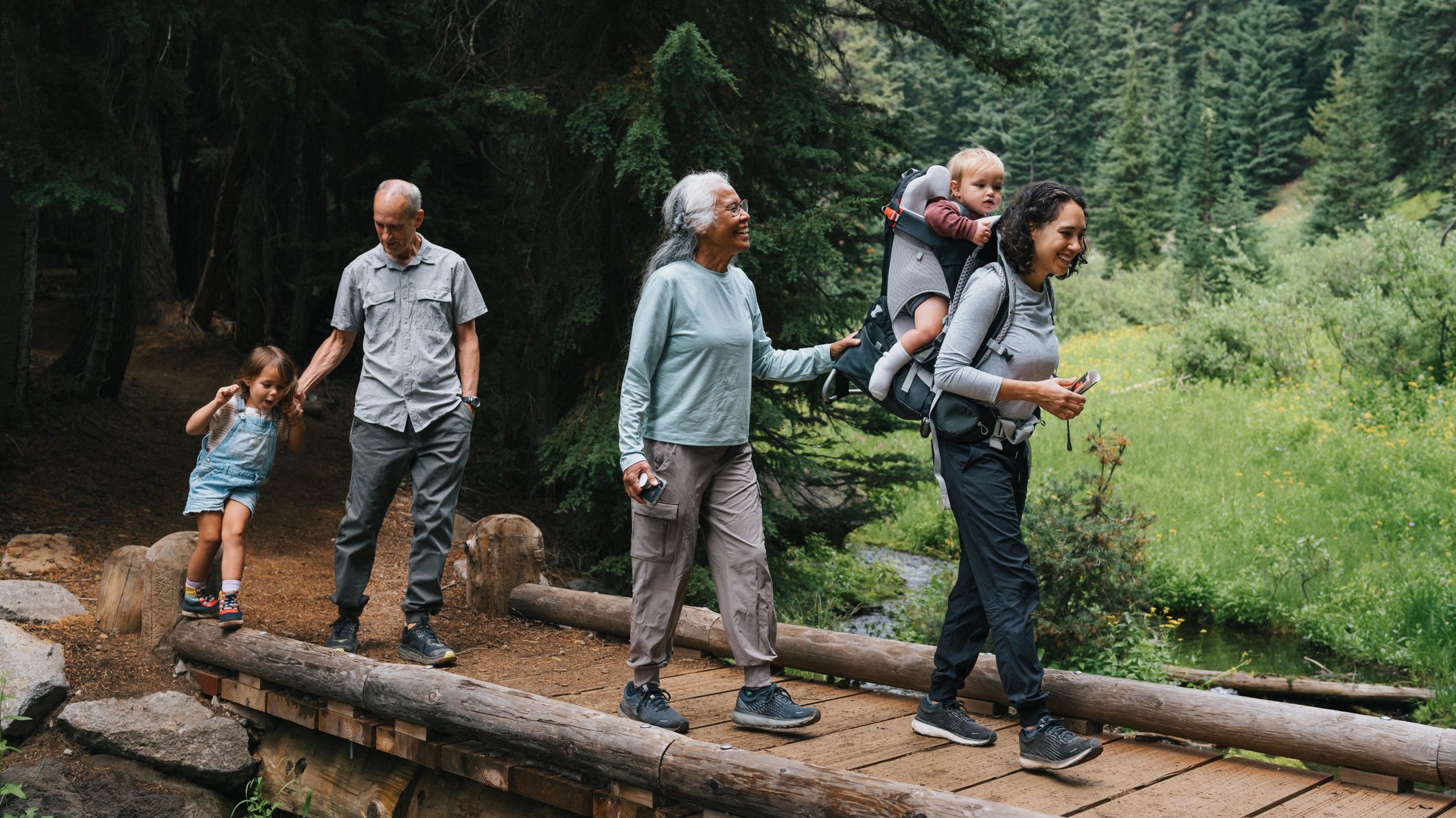An active and happy family hike across a small bridge