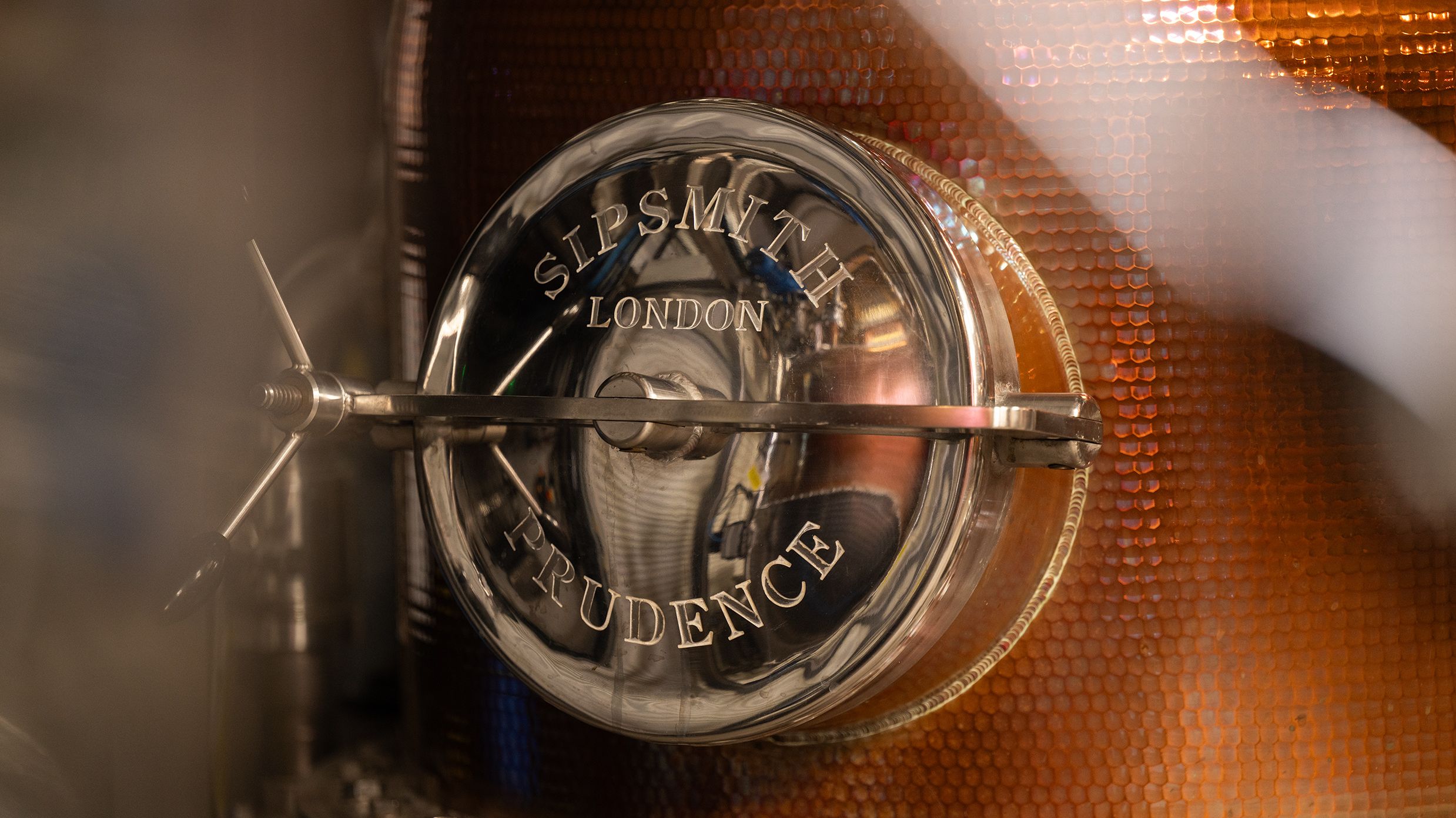 an image of the opening hatch on one o the large copper stills in the distillery