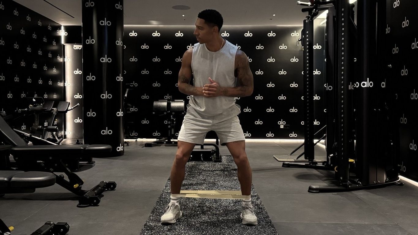 Man demonstrates lateral band walk exercise in gym