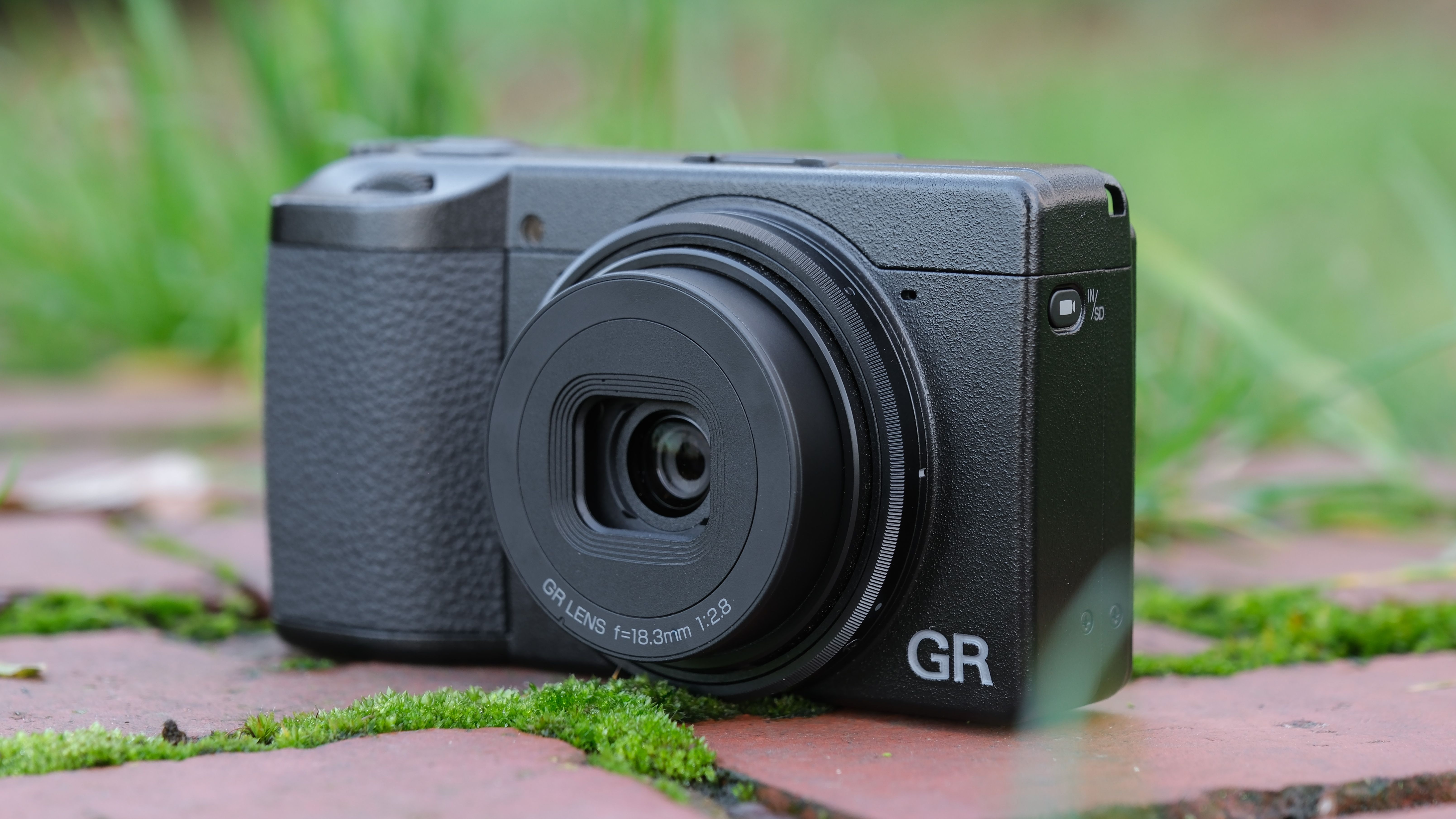 Ricoh GR IV compact camera on a brick wall