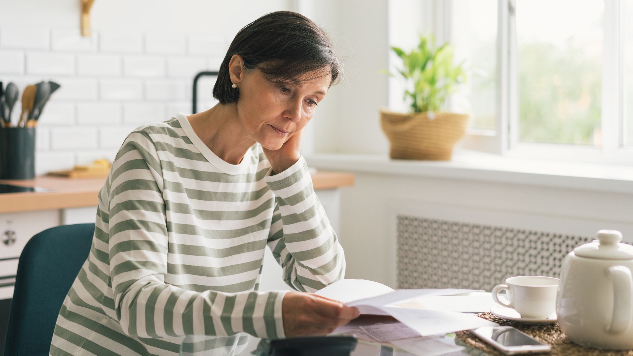 Woman looking at insurance documents at her kitchen table.