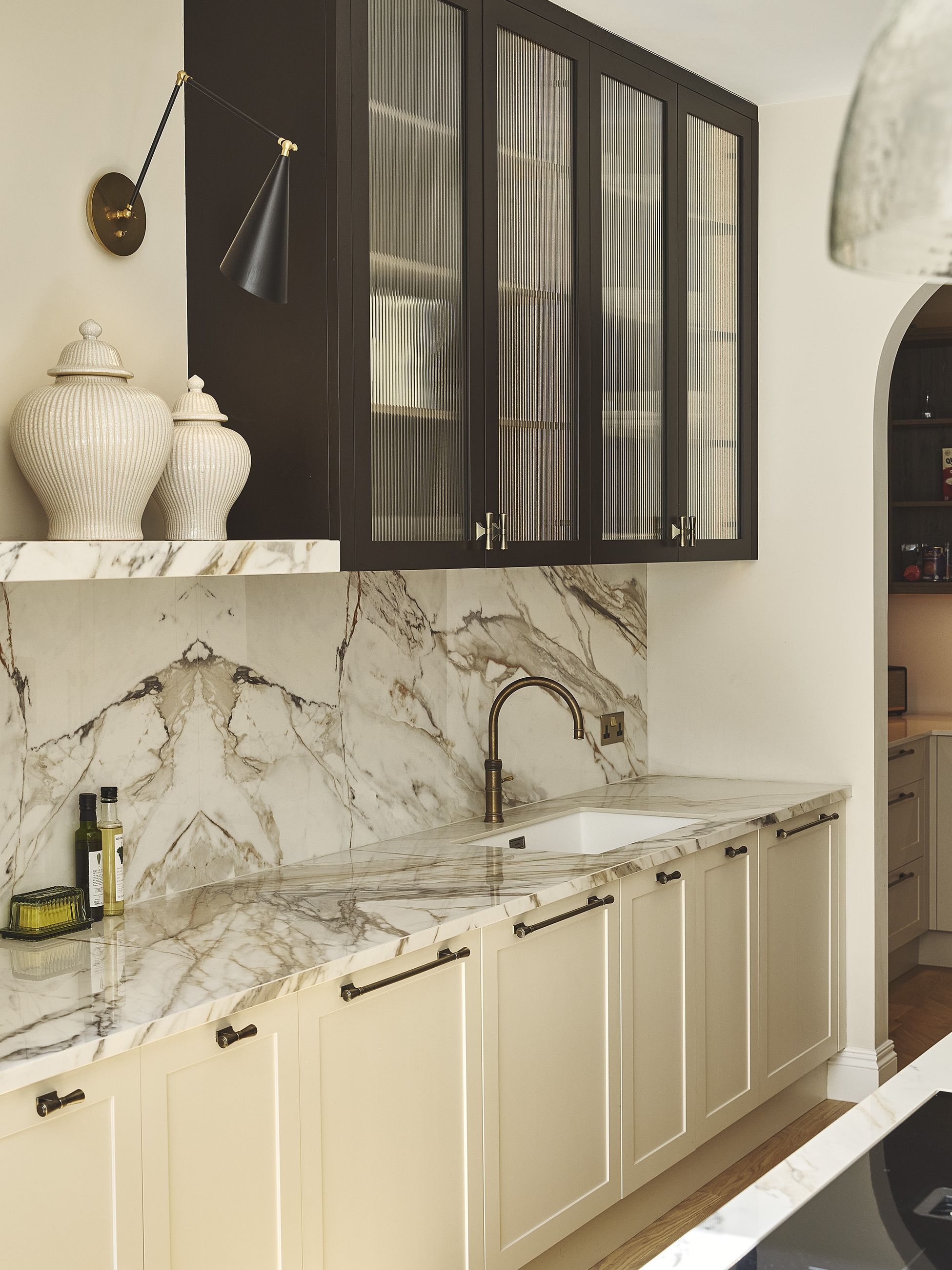A neutral coloured kitchen with marble splashback and black wall cabinets