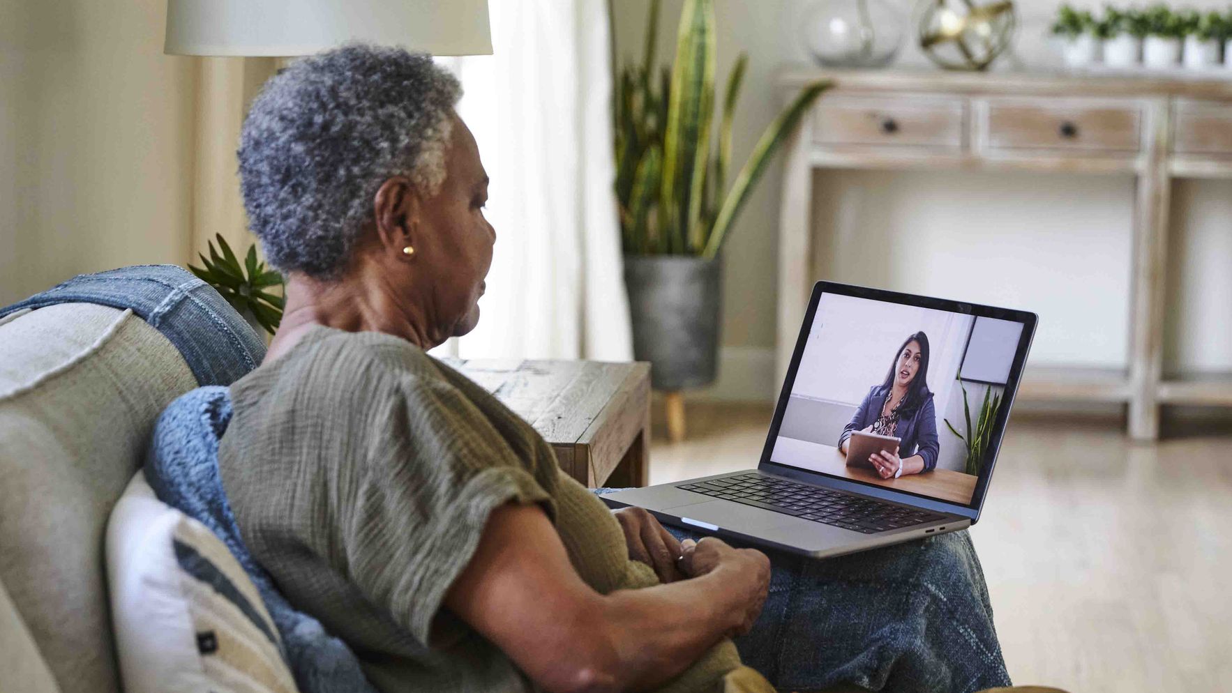 Woman sitting on a couch having a video call on a laptop