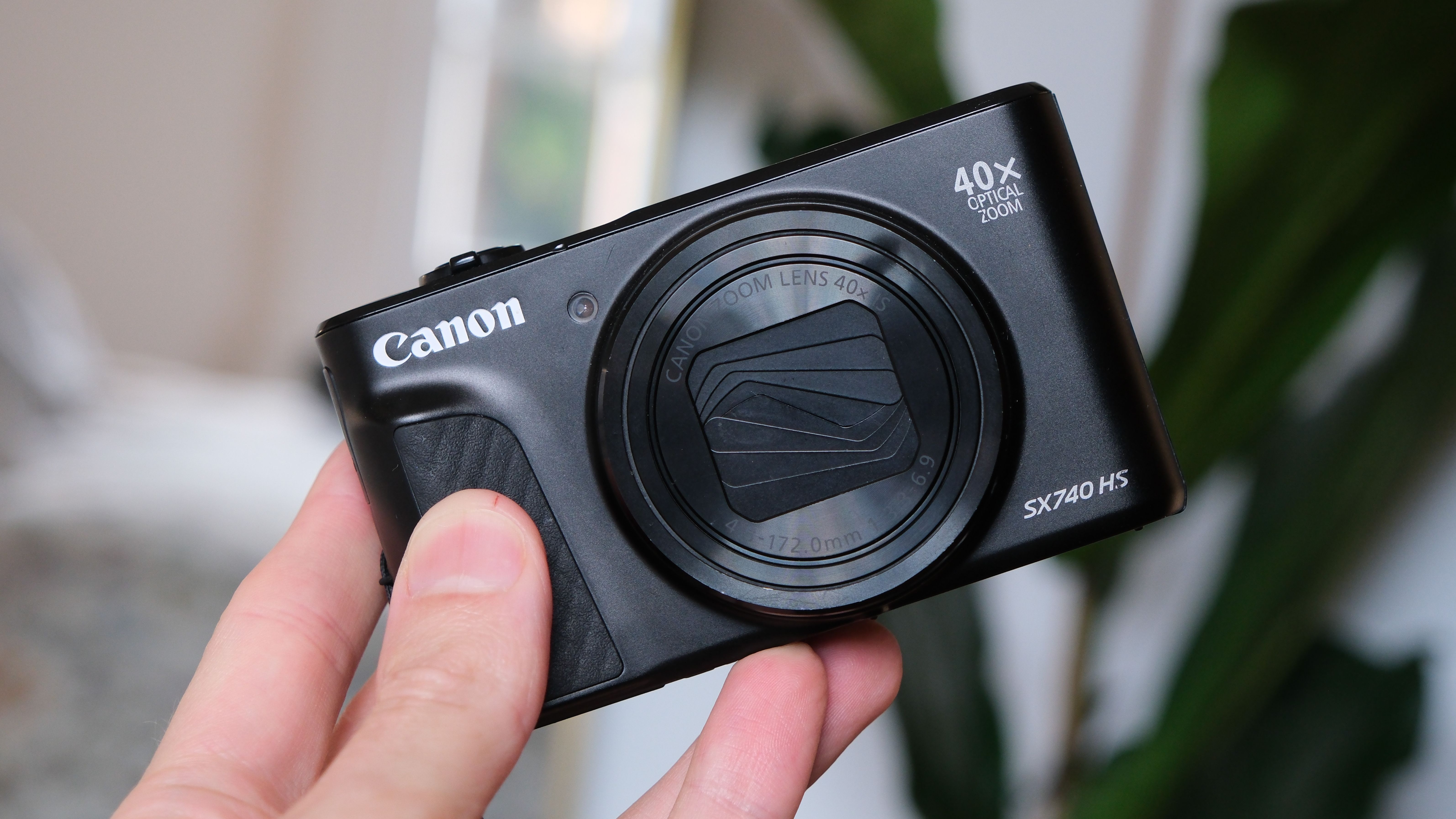 Canon PowerShot SX740 HS compact camera held in a hand