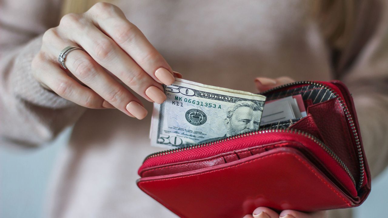 A woman pulls cash from a wallet