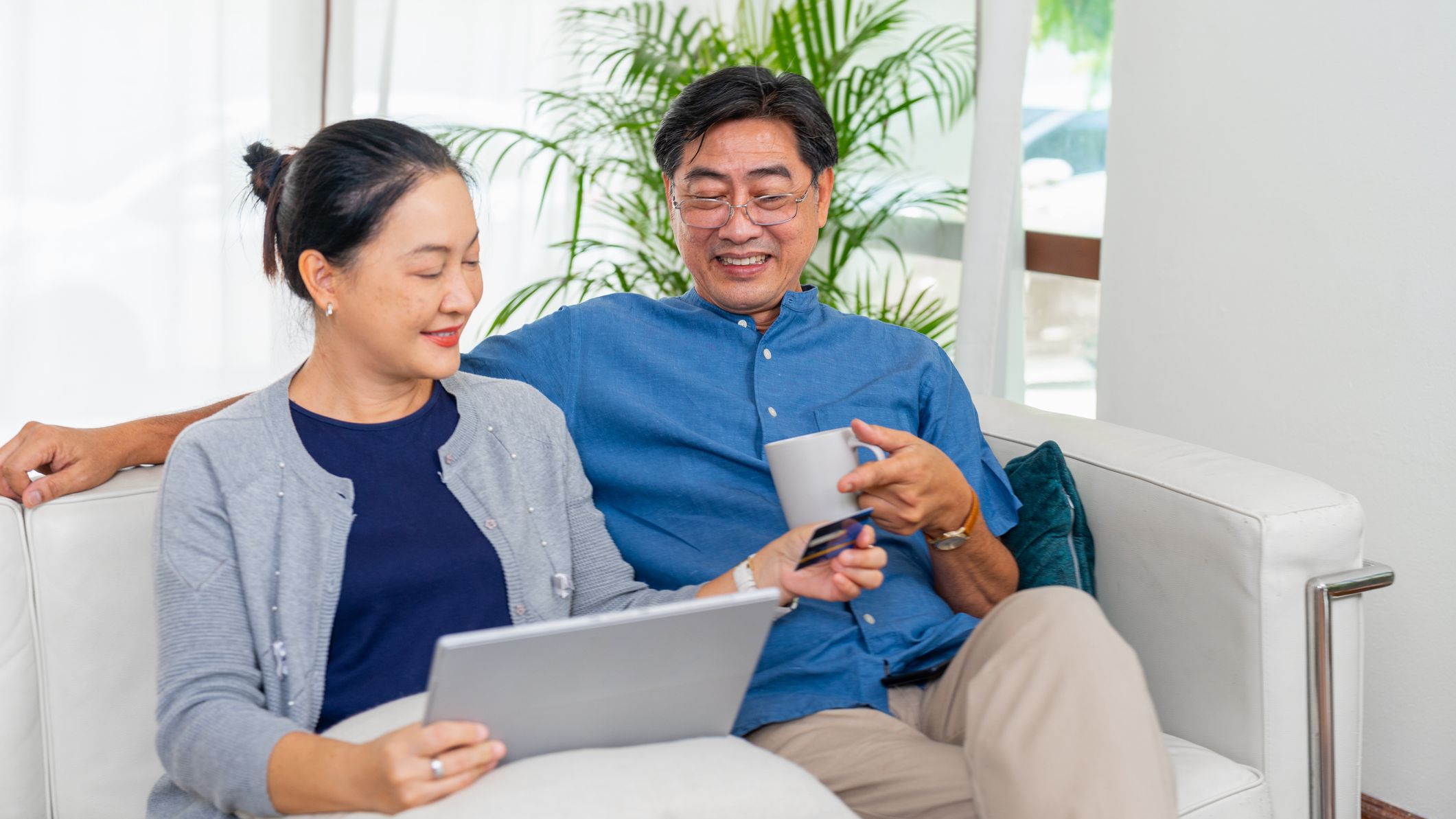 A happy mature couple relaxes on the couch while discussing finances.