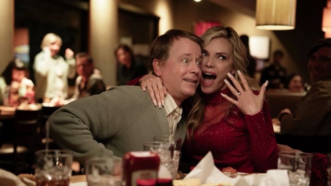 Greg Kinnear and Michelle Pfieffer in Margo's Got Money Troubles. Pfieffer's character is excitedly showing off her engagement ring.