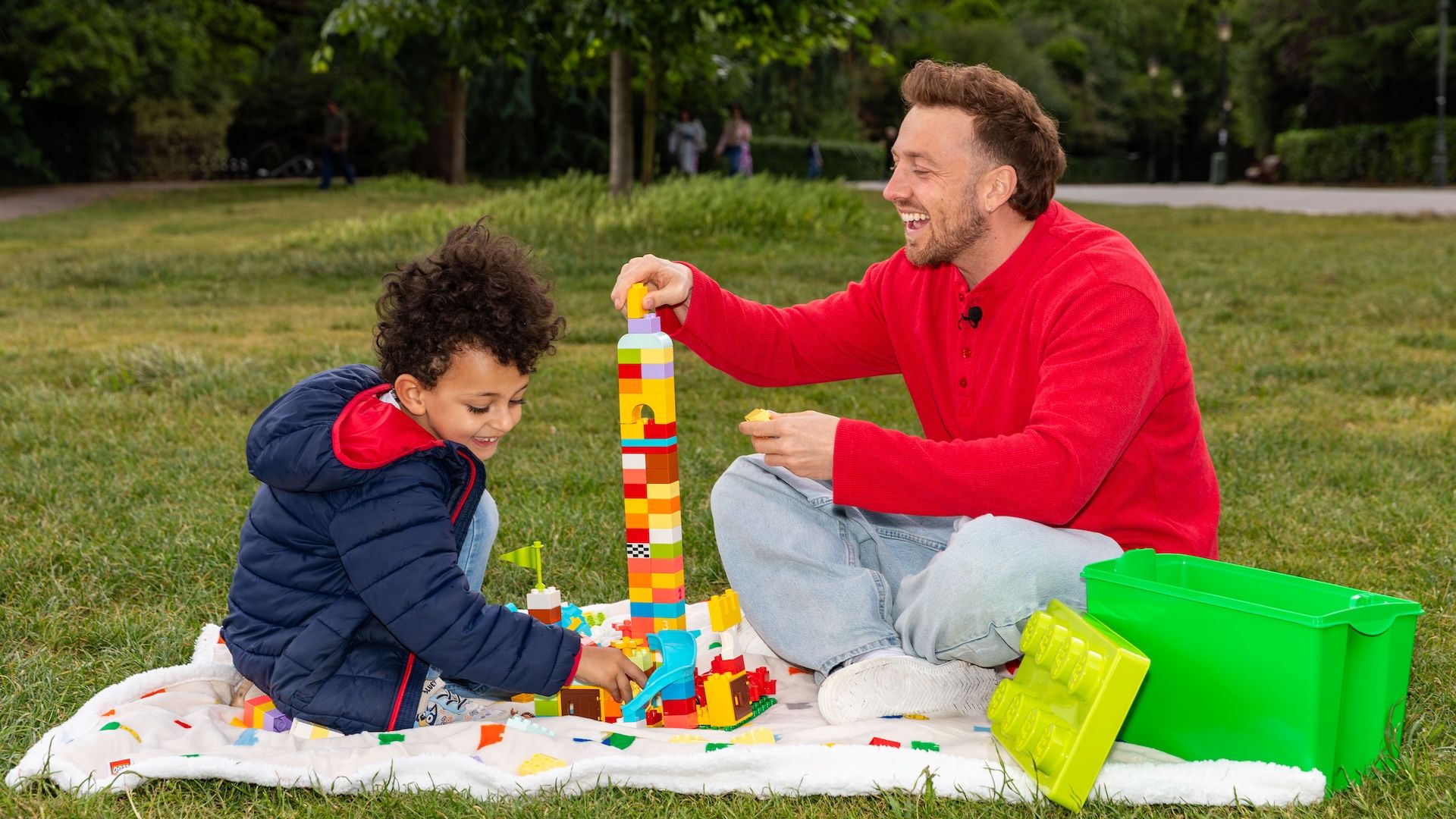 Sam Thompson building a LEGO tower with a boy in the park